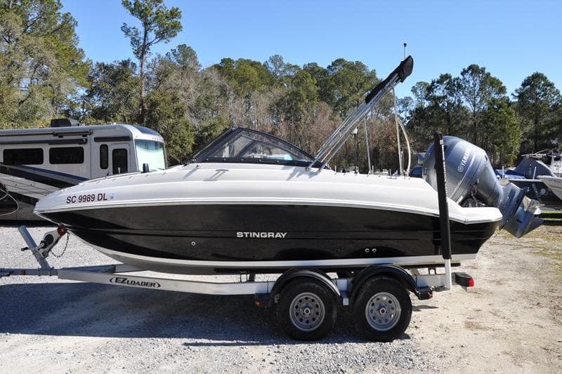 2021 Stingray 201 DS boat on trailer, parked outdoors with trees in background.