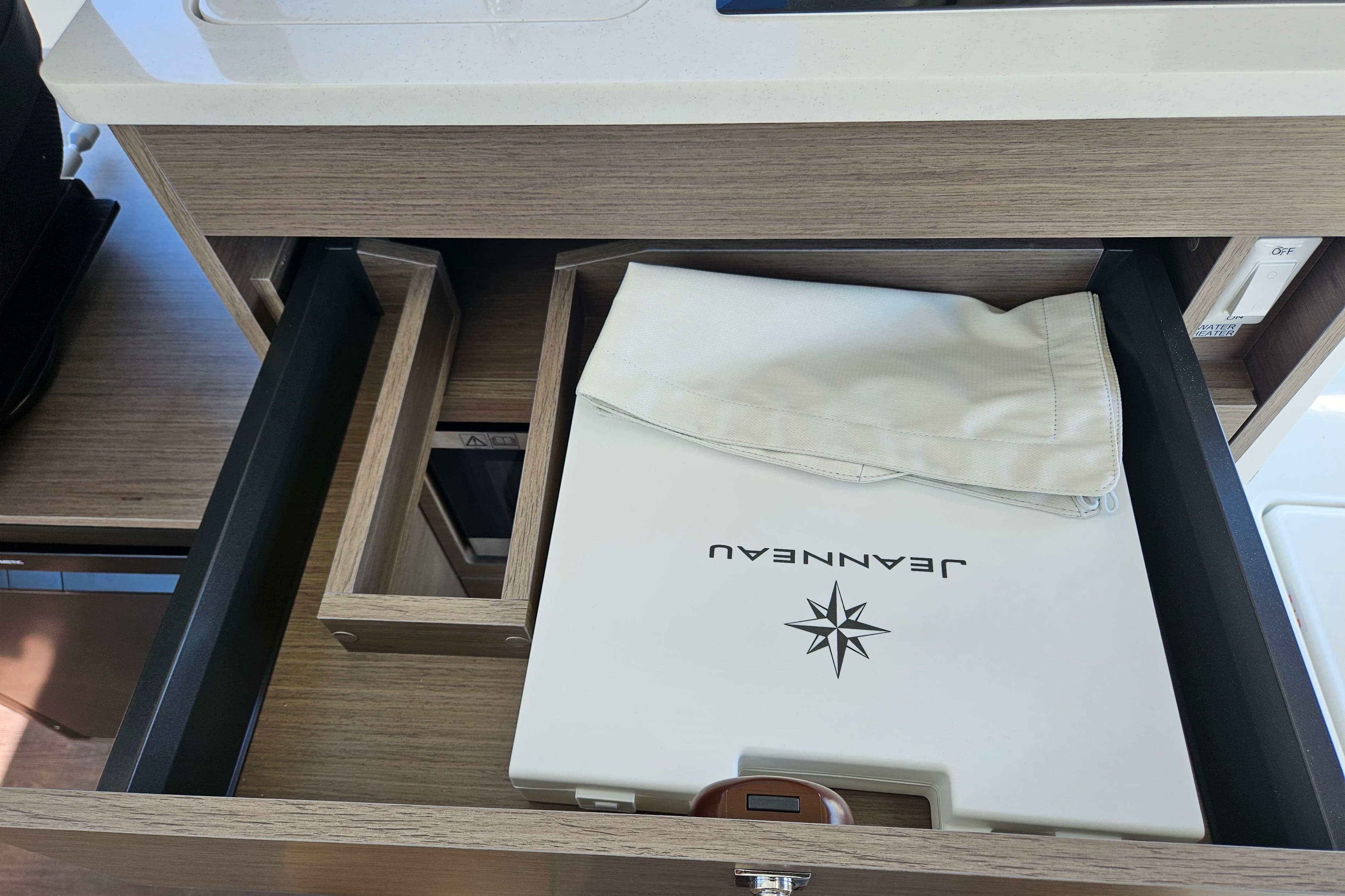 Open drawer in Jeanneau NC 895 Sport Series 2, showcasing branded storage.
