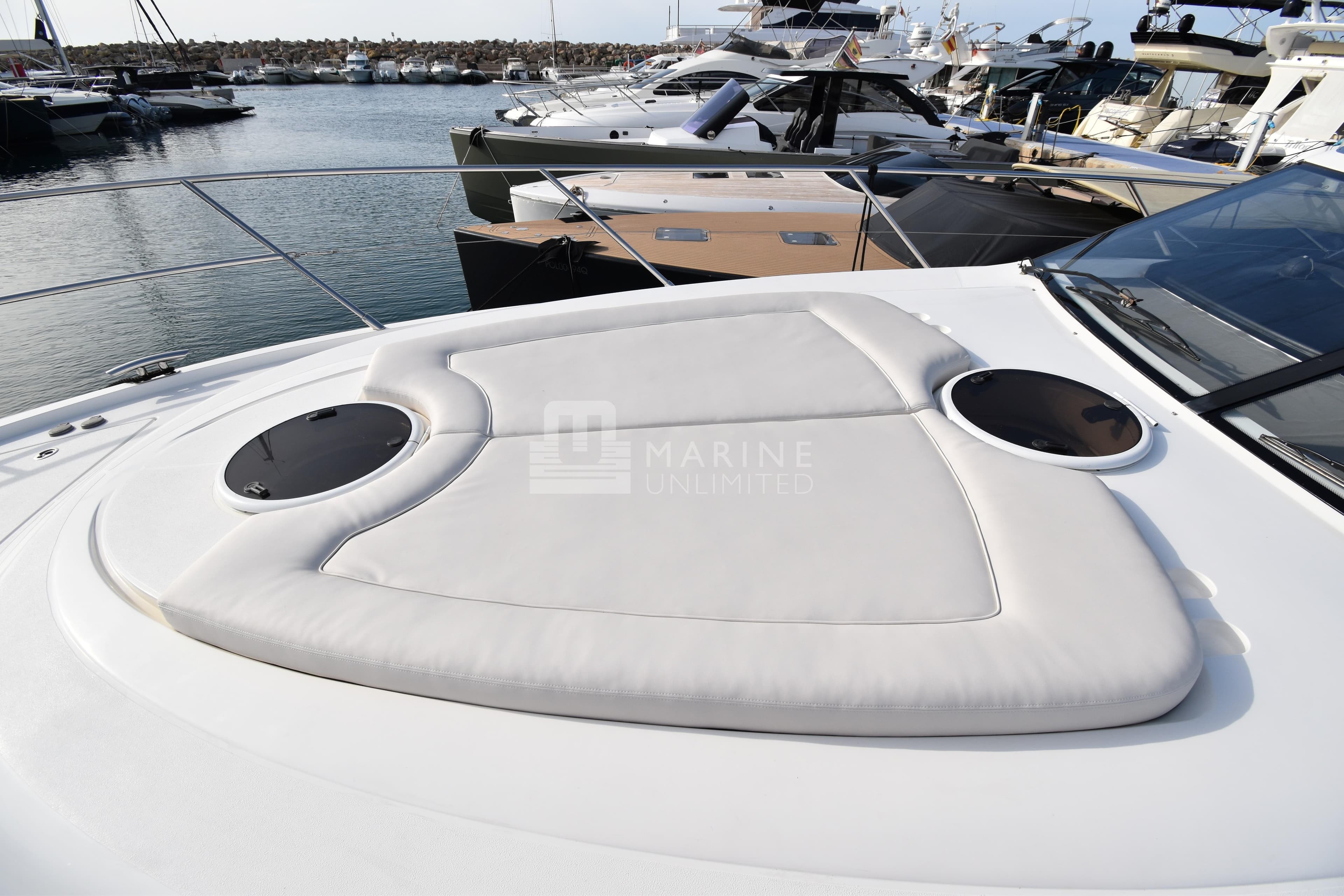 2012 Princess V42 yacht with cushioned sun deck, docked in a marina.