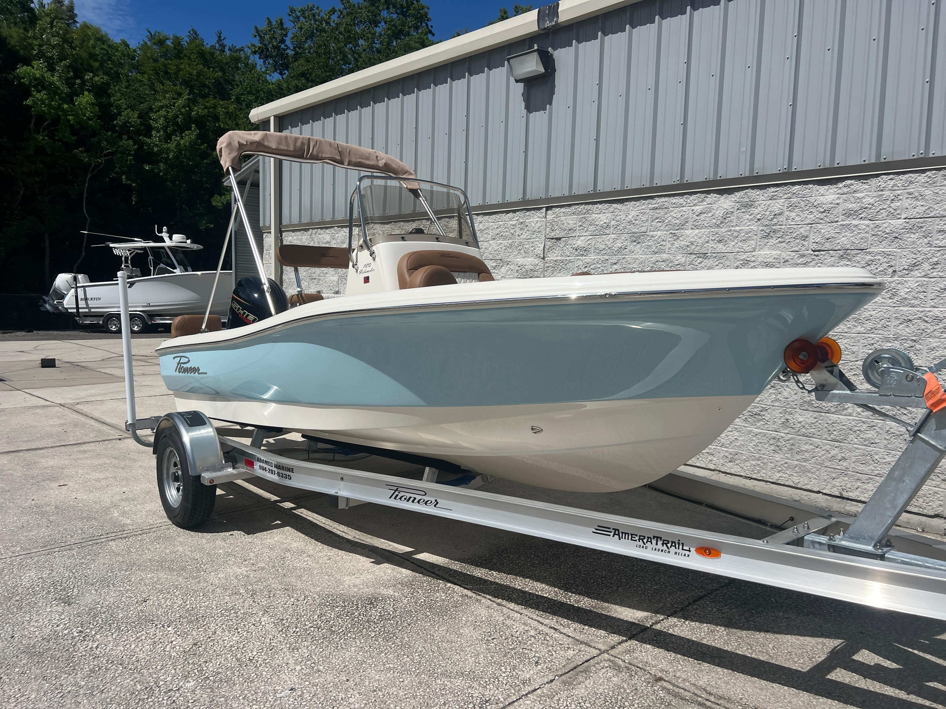 2026 Pioneer 180 Islander boat on trailer, parked outdoors near a building.