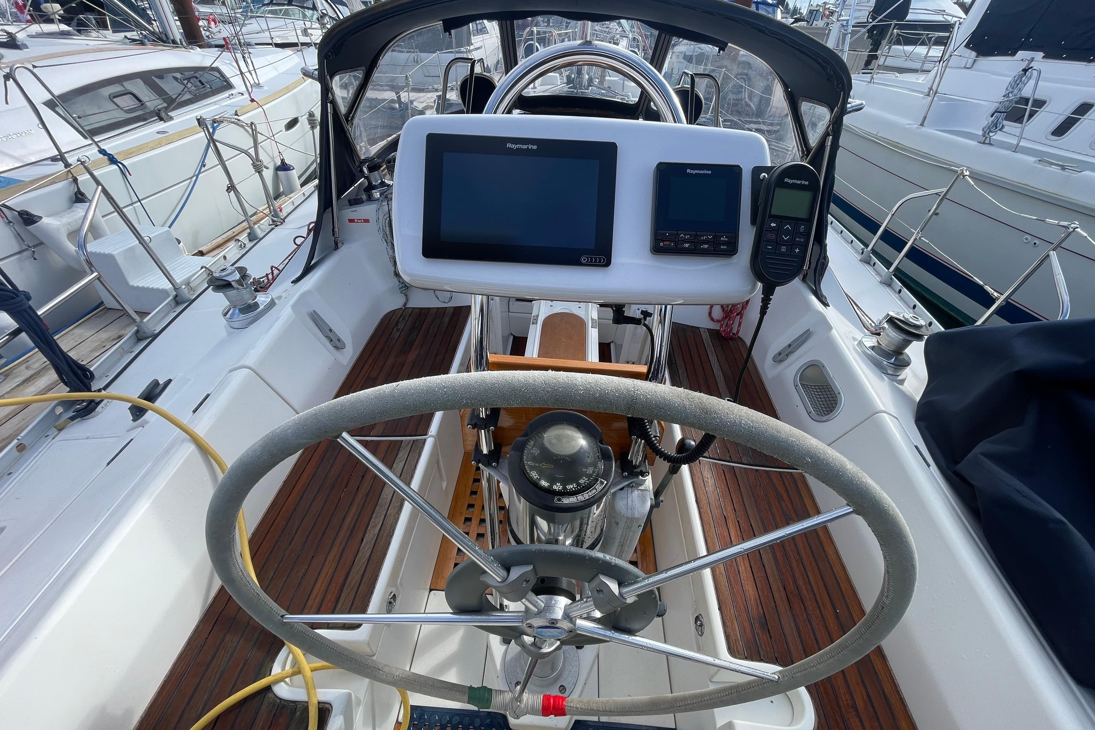 Cockpit of 1990 Beneteau Oceanis 390 sailboat with navigation equipment and steering wheel.