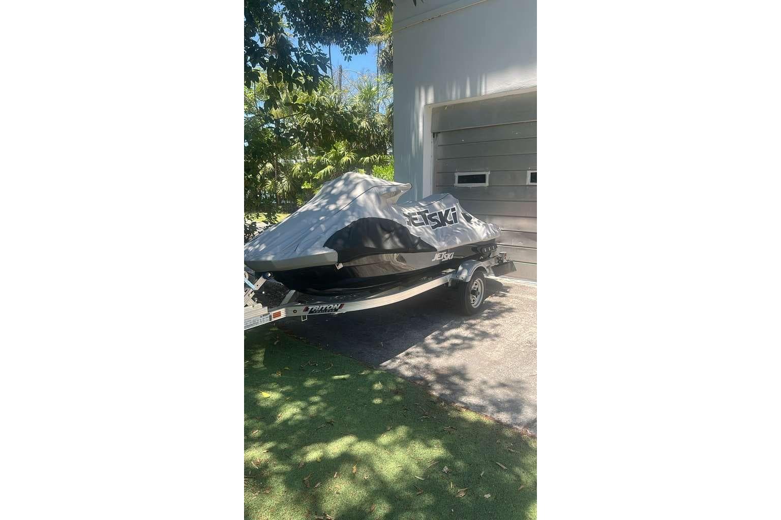 2023 Kawasaki Jetski Ultra 310LX covered and parked on a trailer in a driveway.