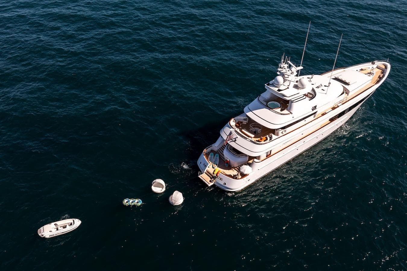 Luxurious 2001 Feadship Custom yacht on open sea with small boats nearby.