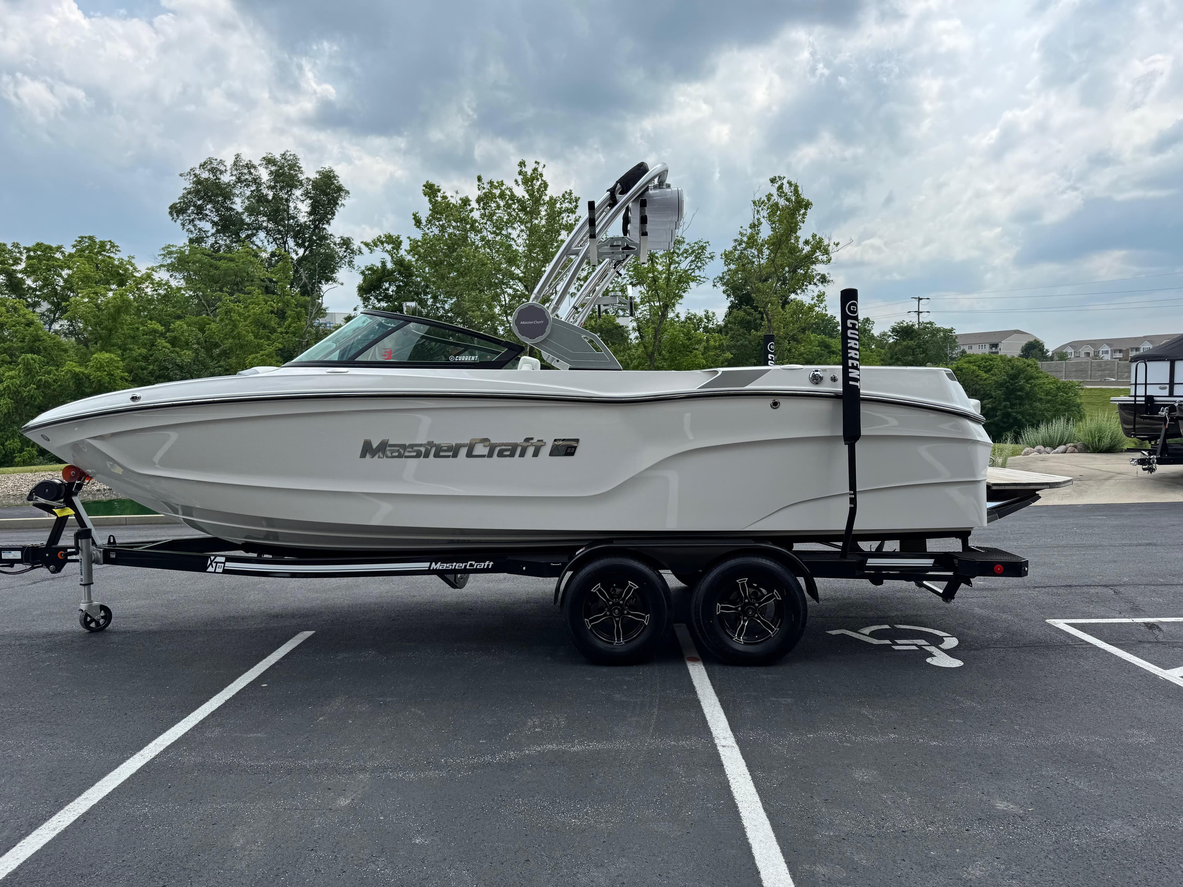 2023 MasterCraft XT23 boat on trailer in parking lot, cloudy sky background.