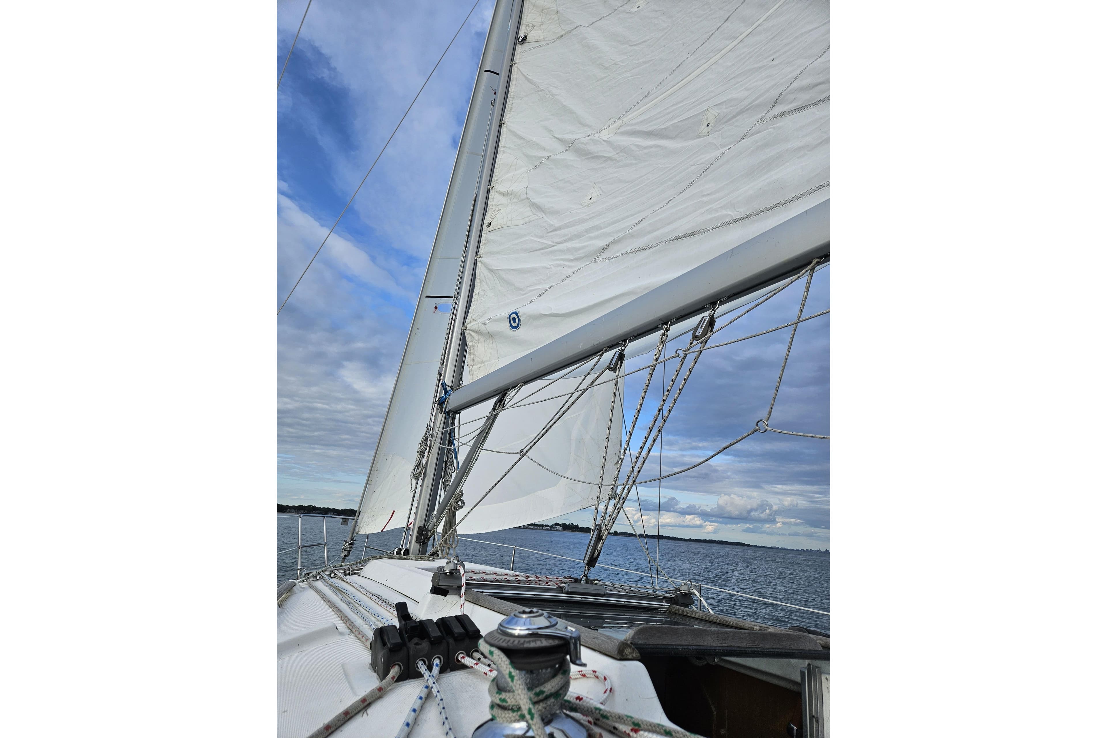 Sailing on a 2003 Beneteau 311 yacht with white sails against a blue sky.