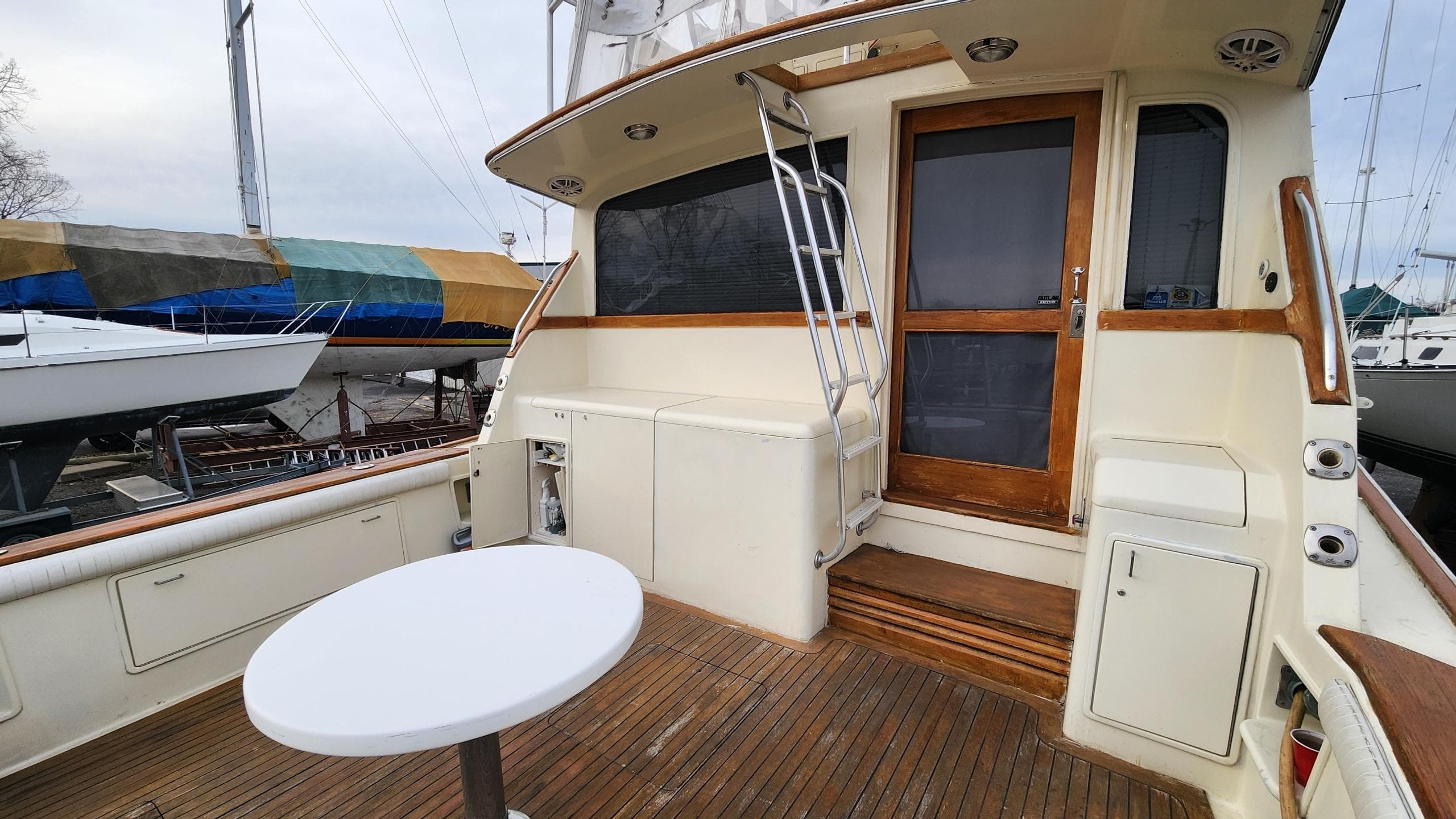 1989 Ocean Yachts 55 deck with wooden flooring and round table, docked near other boats.