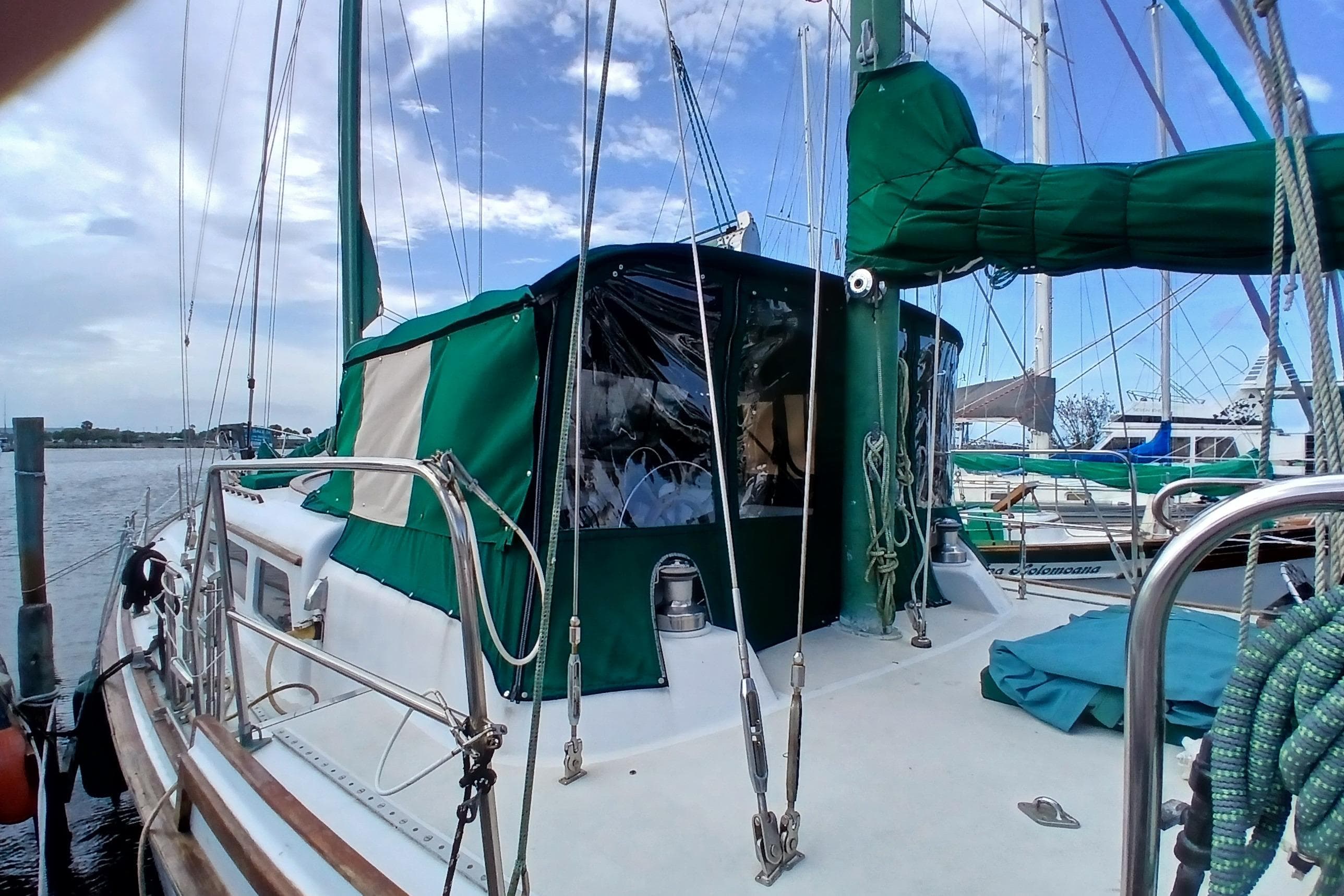 1981 Wellington 44 Center Cockpit sailboat docked, featuring green canvas covers and rigging.