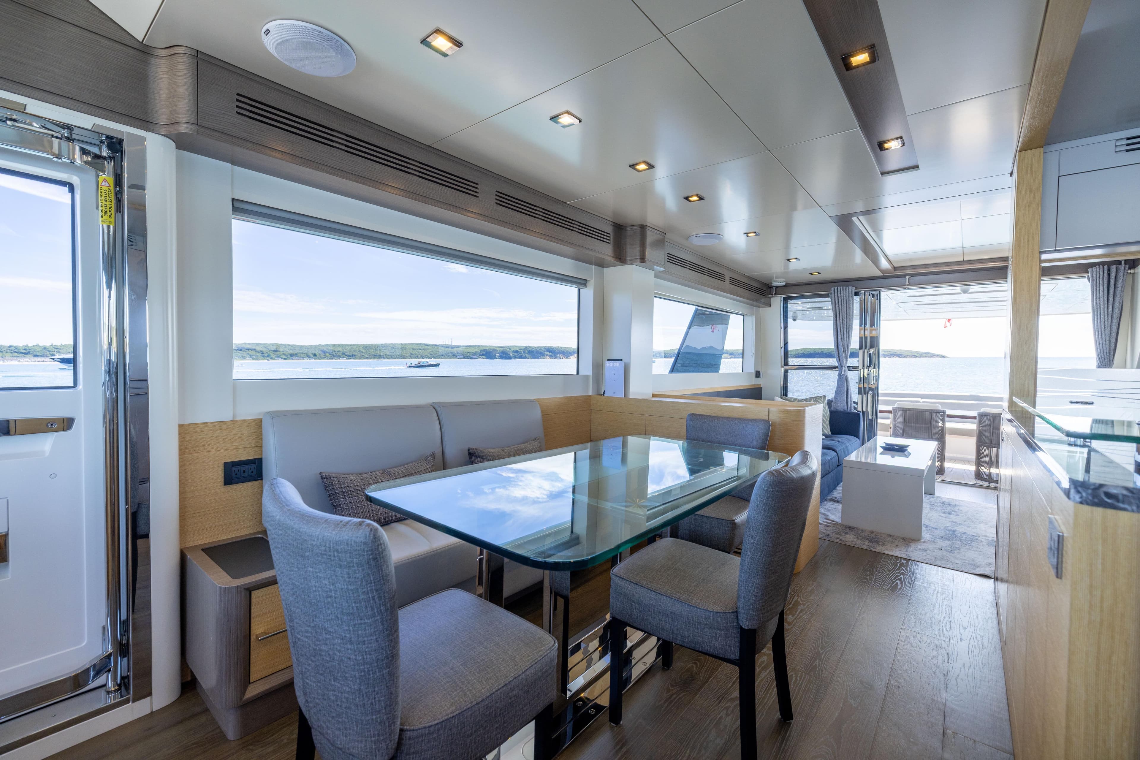 Luxurious interior of 2019 Sirena 64 yacht with modern dining area and scenic ocean views.