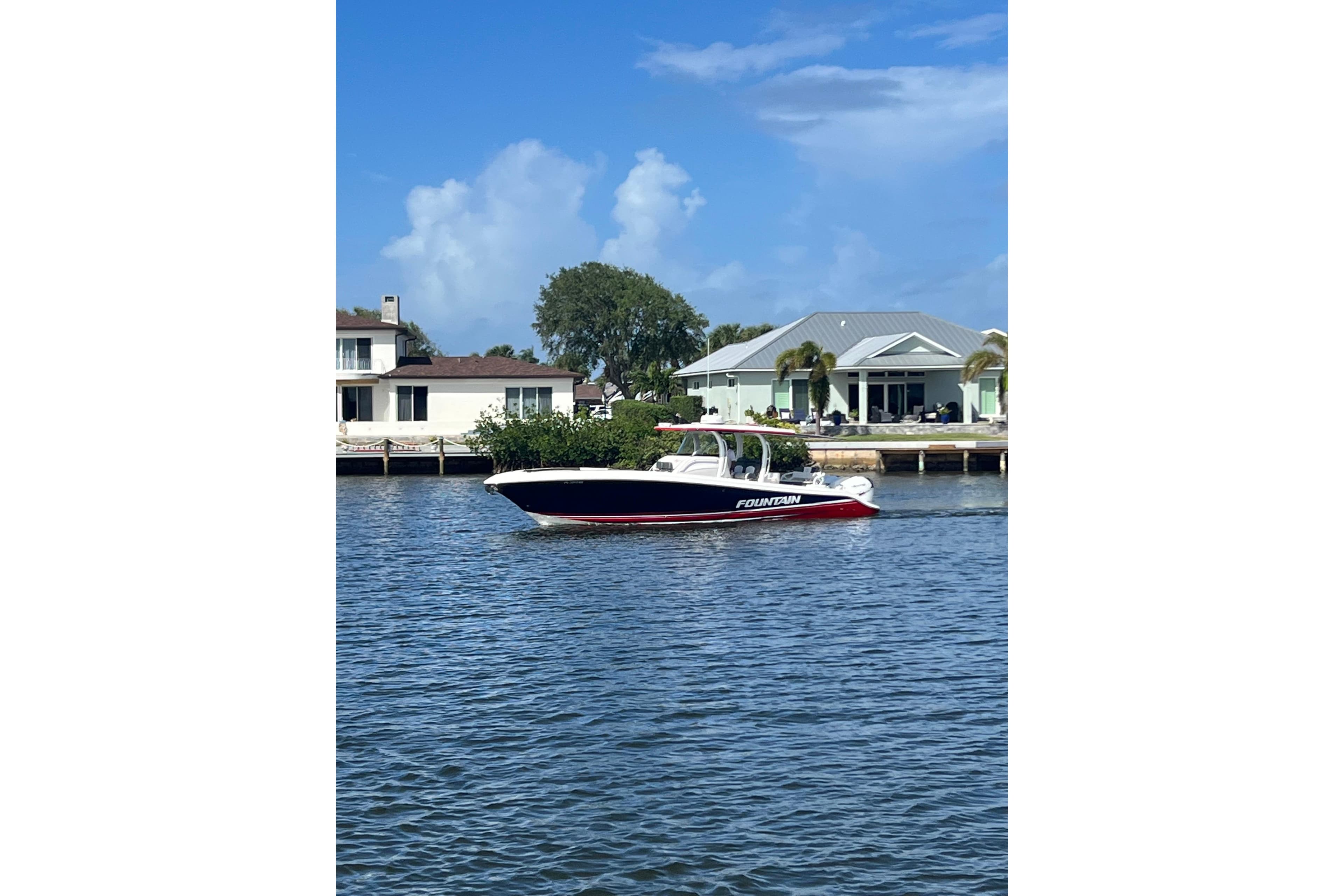 2021 Fountain 39 NX boat cruising on a scenic waterfront with houses in the background.