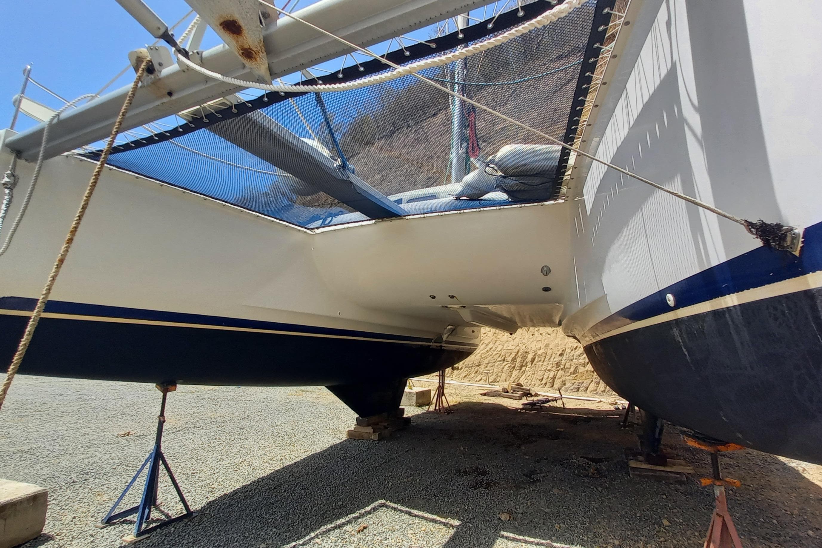 2008 Lagoon 380 S2 catamaran on dry dock, showcasing hull and netting details.