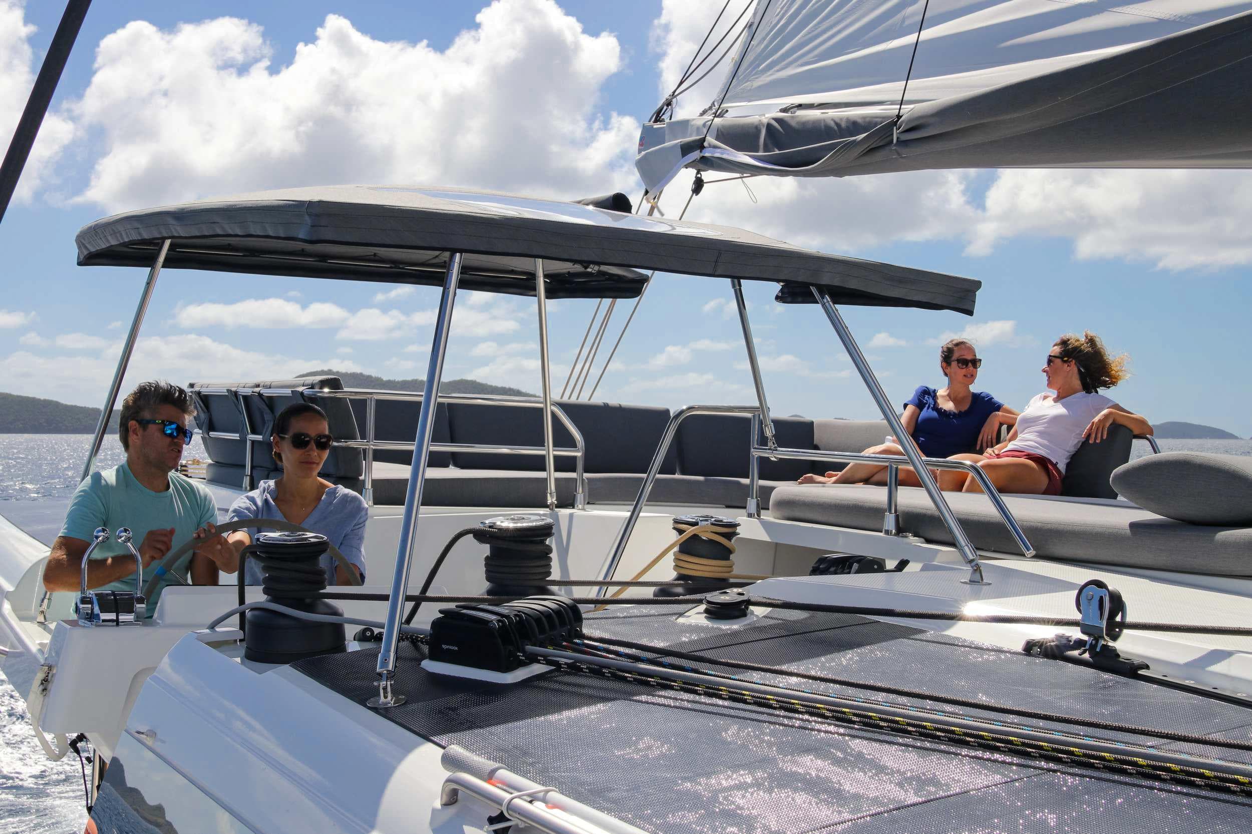 People relaxing on a 2022 Fountaine Pajot Catamaran Aura 51 under sunny skies.