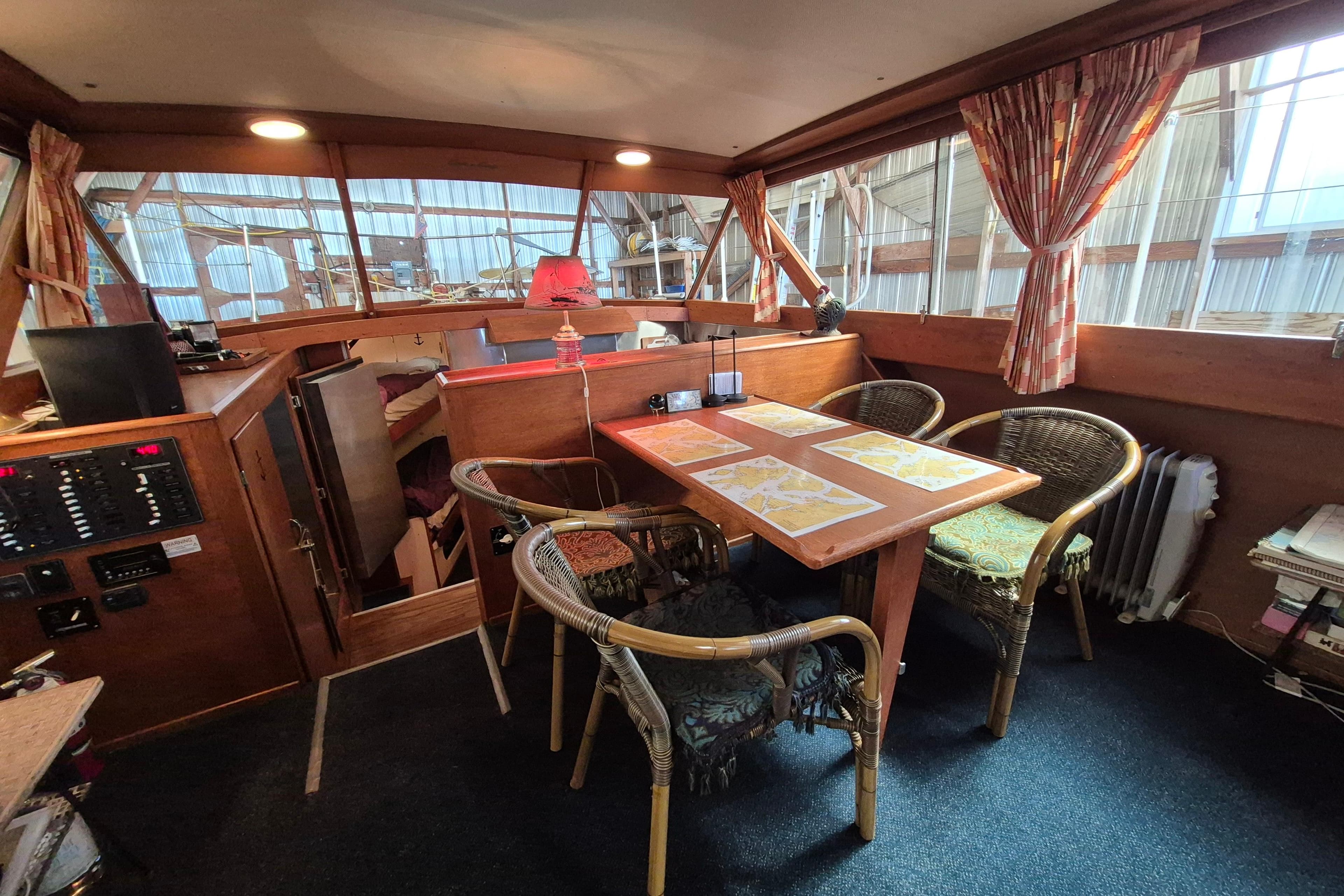 Interior of 1958 Chris-Craft 500 Constellation yacht with dining area and wicker chairs.