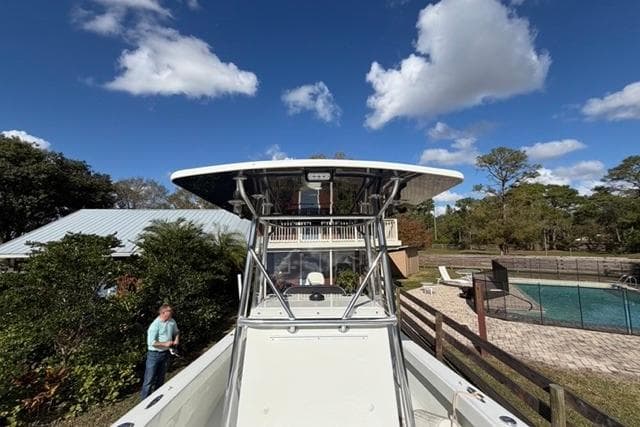 2017 Stuart 27 boat near a house and pool under a clear blue sky.