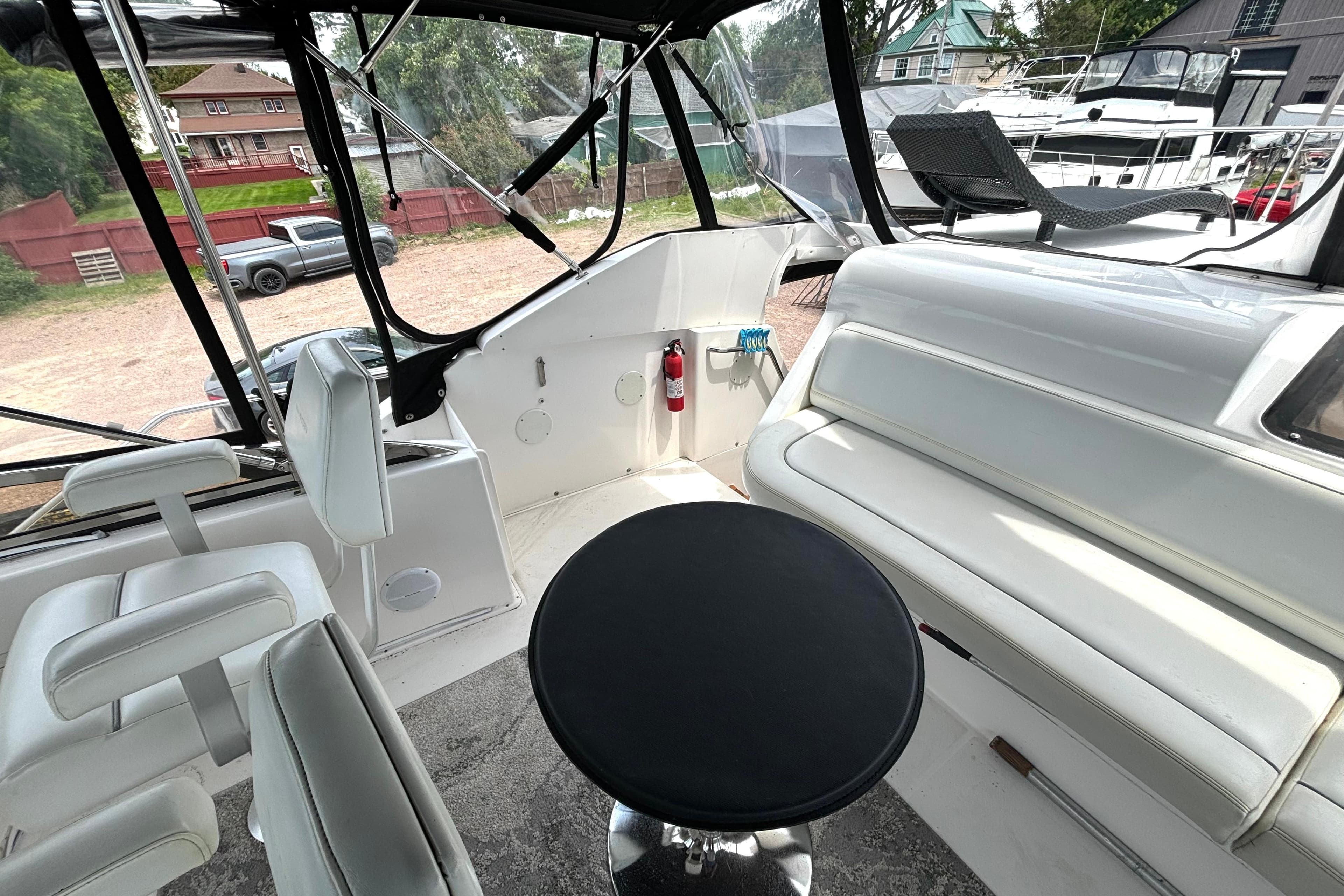 Interior view of a 1999 Silverton 453 Motor Yacht with white seating and a black table.