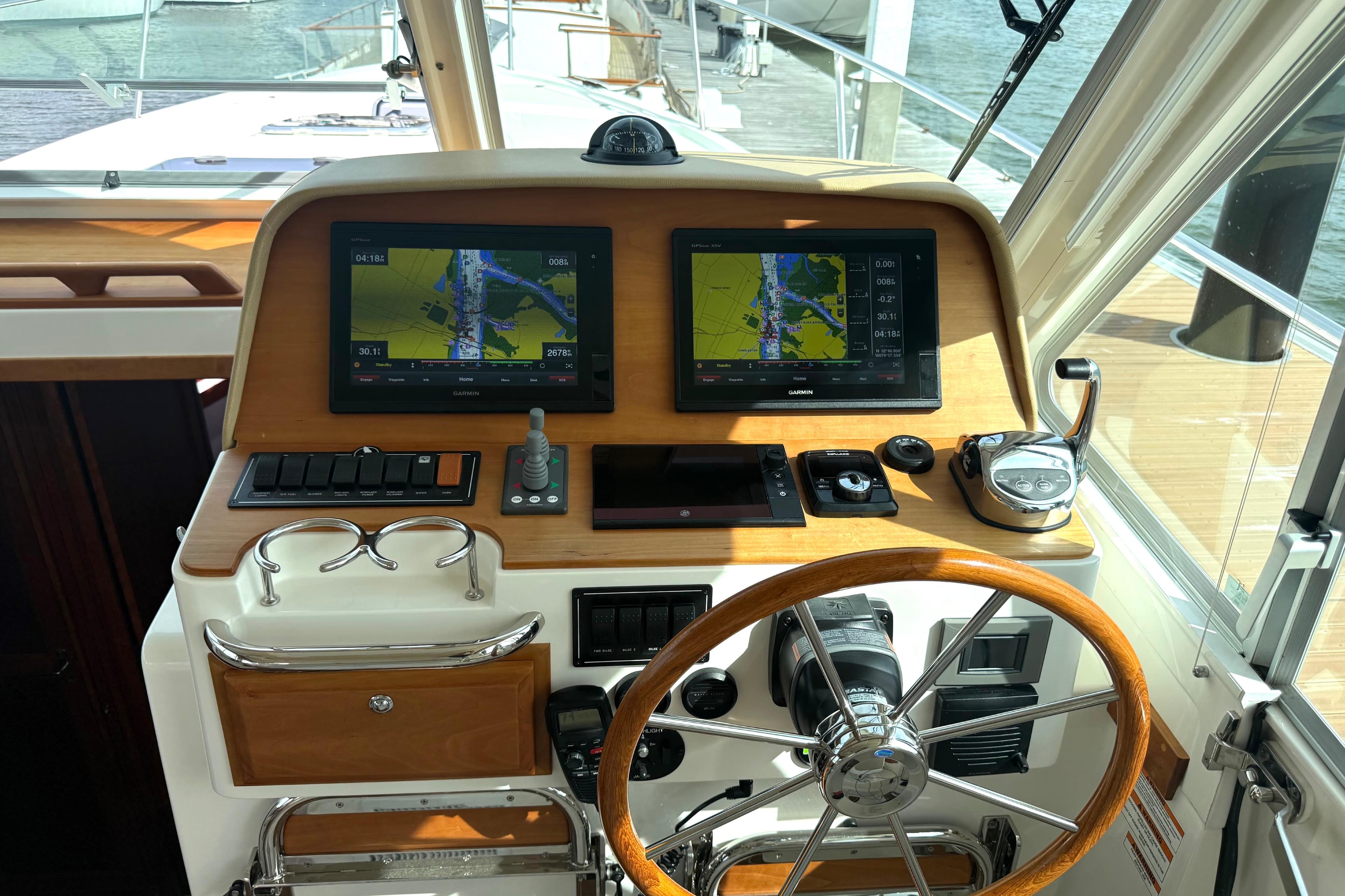 Helm of 2018 Back Cove 41 boat with navigation screens and wooden steering wheel.