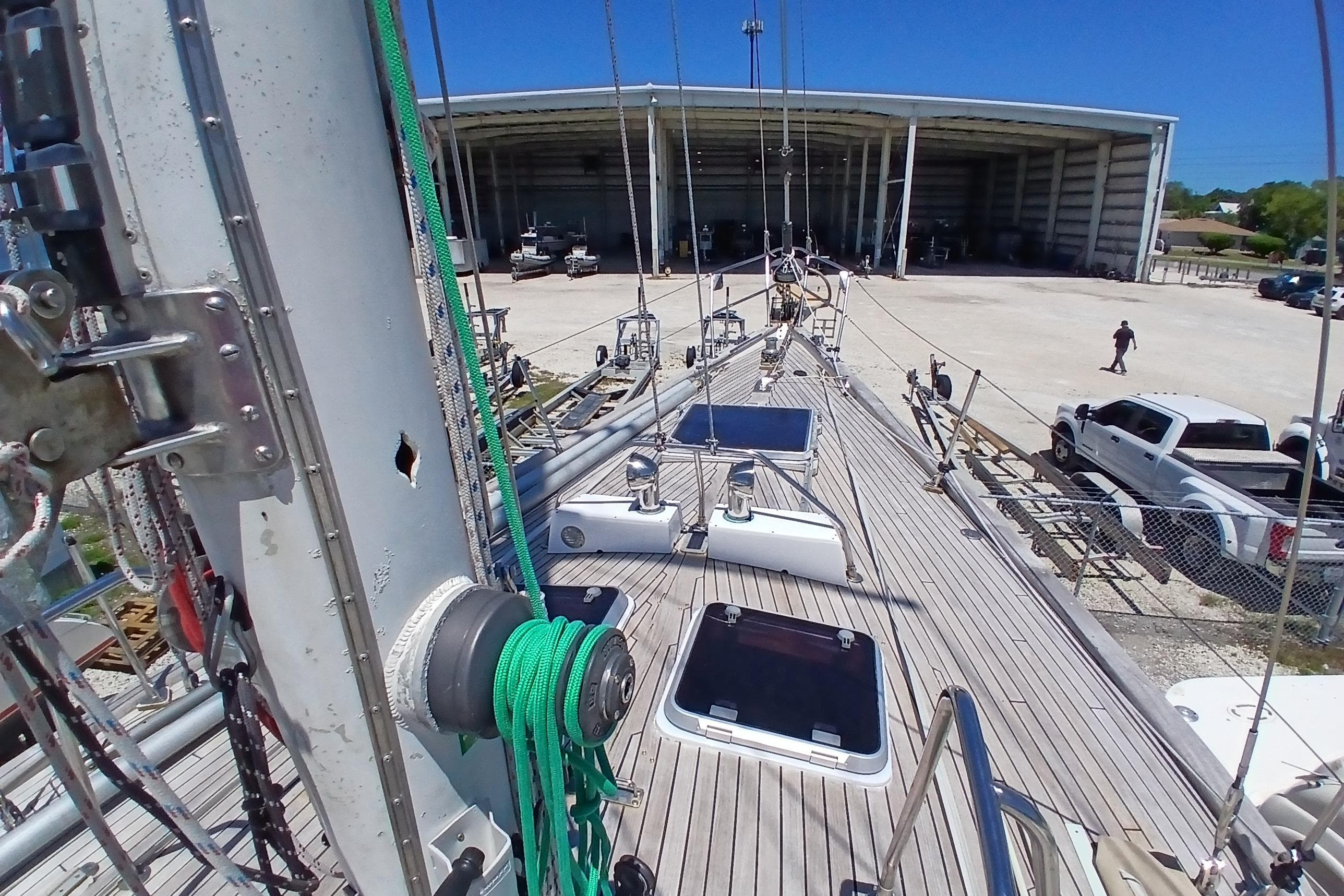 Deck view of 1981 Kaufman Skye 51 sailboat at a marina with trucks nearby.