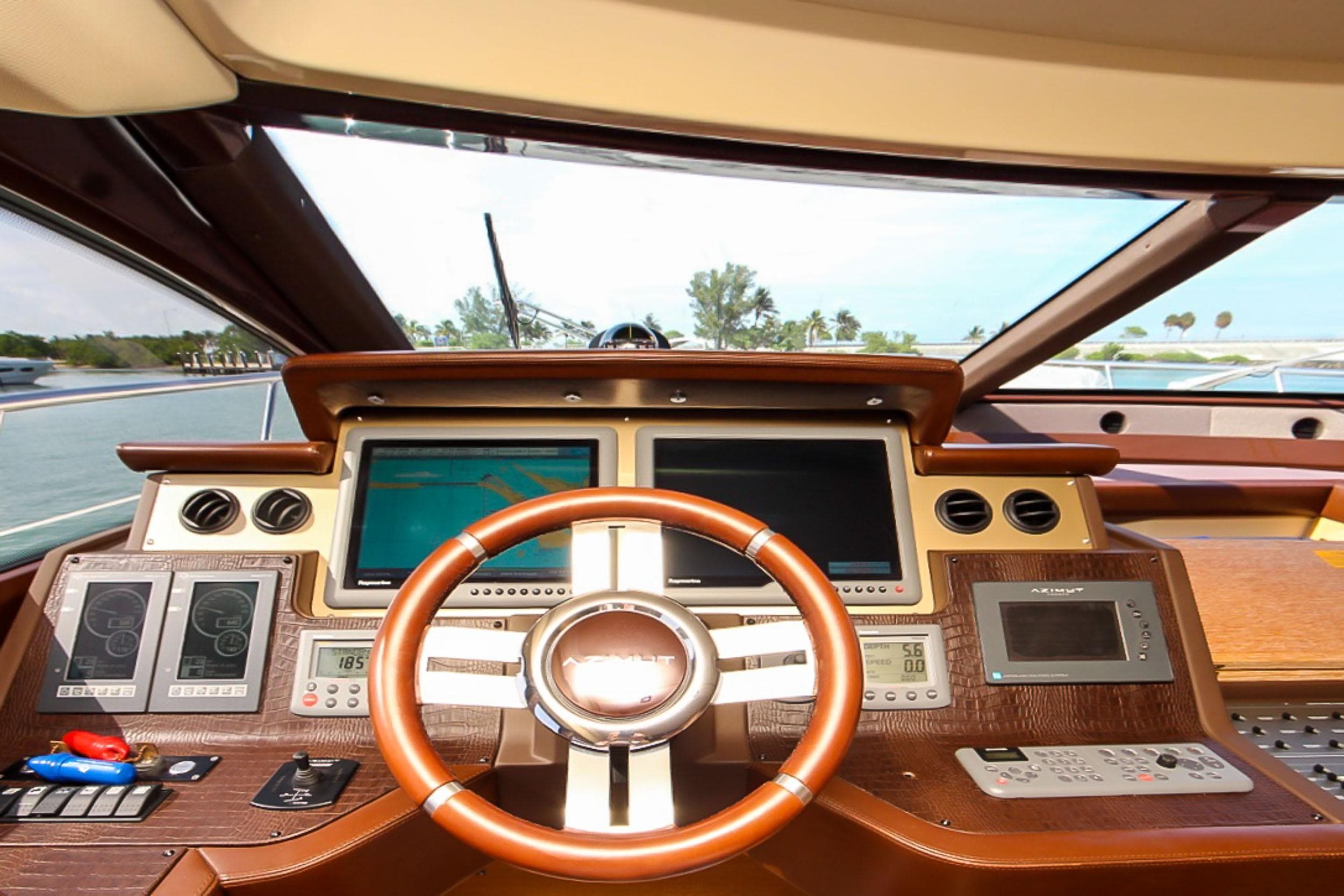 Helm of 2011 Azimut 70 yacht with modern navigation equipment and wooden steering wheel.
