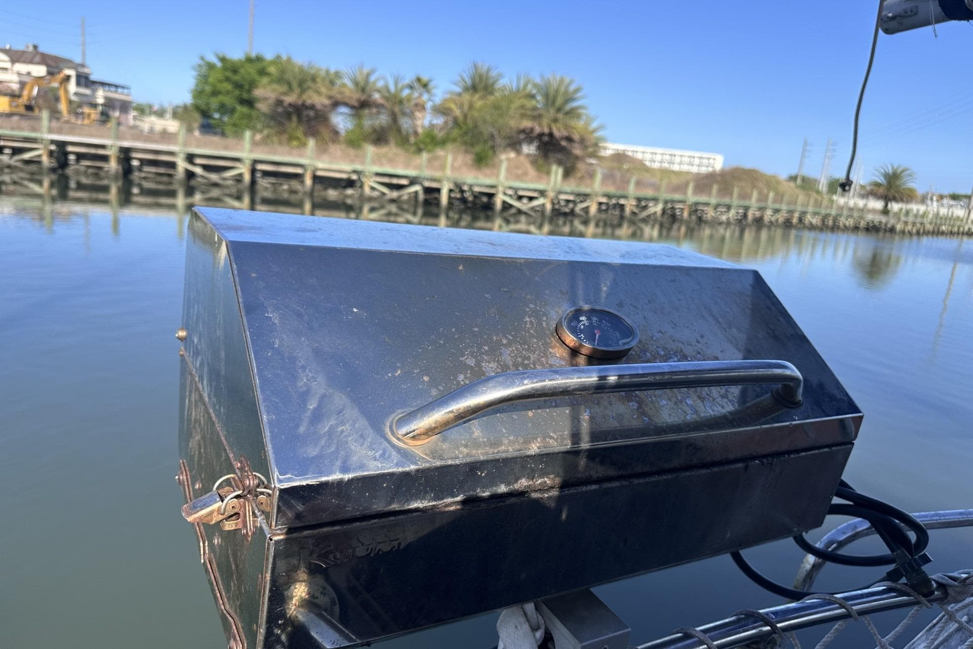 Stainless steel grill on a Pearson 424 sailboat, docked by calm waters, sunny day.