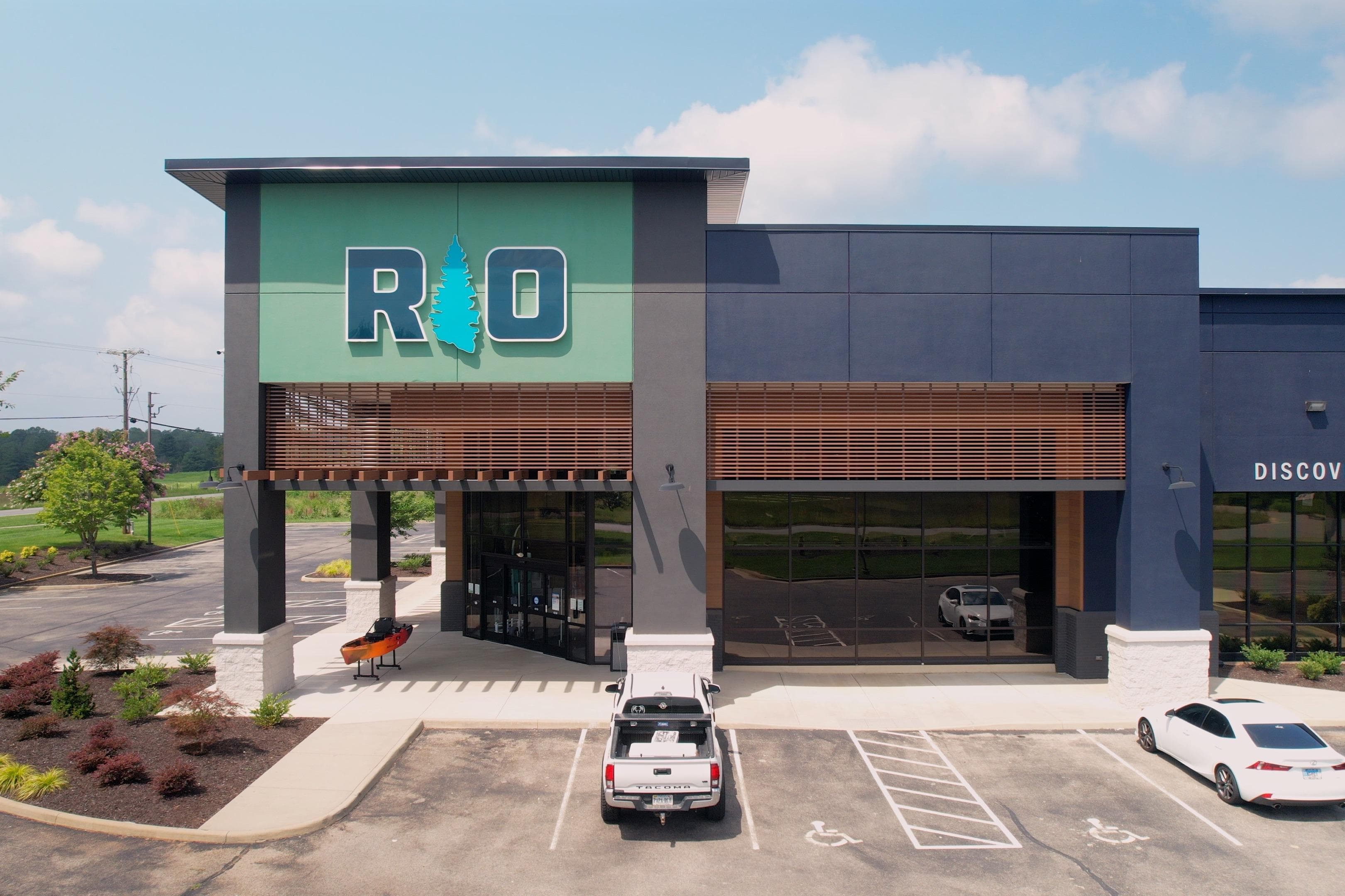 Outdoor retail store entrance with modern design, featuring large "R O" signage and parking area.