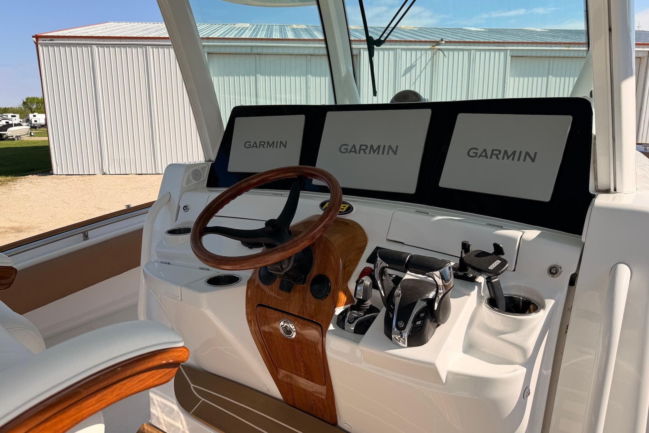 Helm of 2022 HCB 42 Lujo boat with Garmin displays and wooden steering wheel.