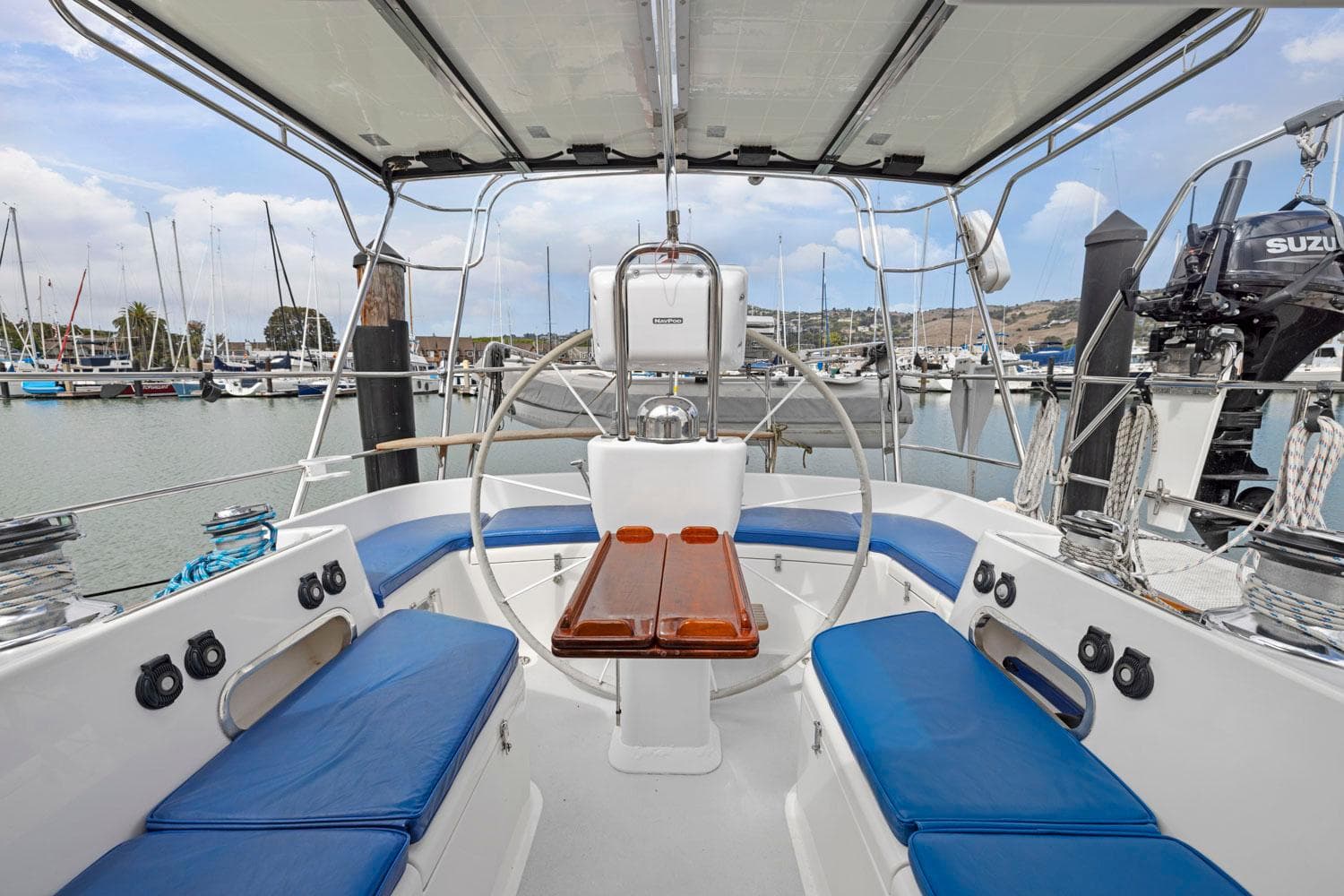 Sailboat cockpit with blue cushions, wooden table, and marina view; Morris 486, 2005 model.