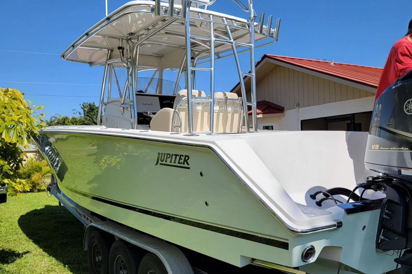 2008 Jupiter 34 FS boat with dual engines on a trailer, parked in a sunny yard.