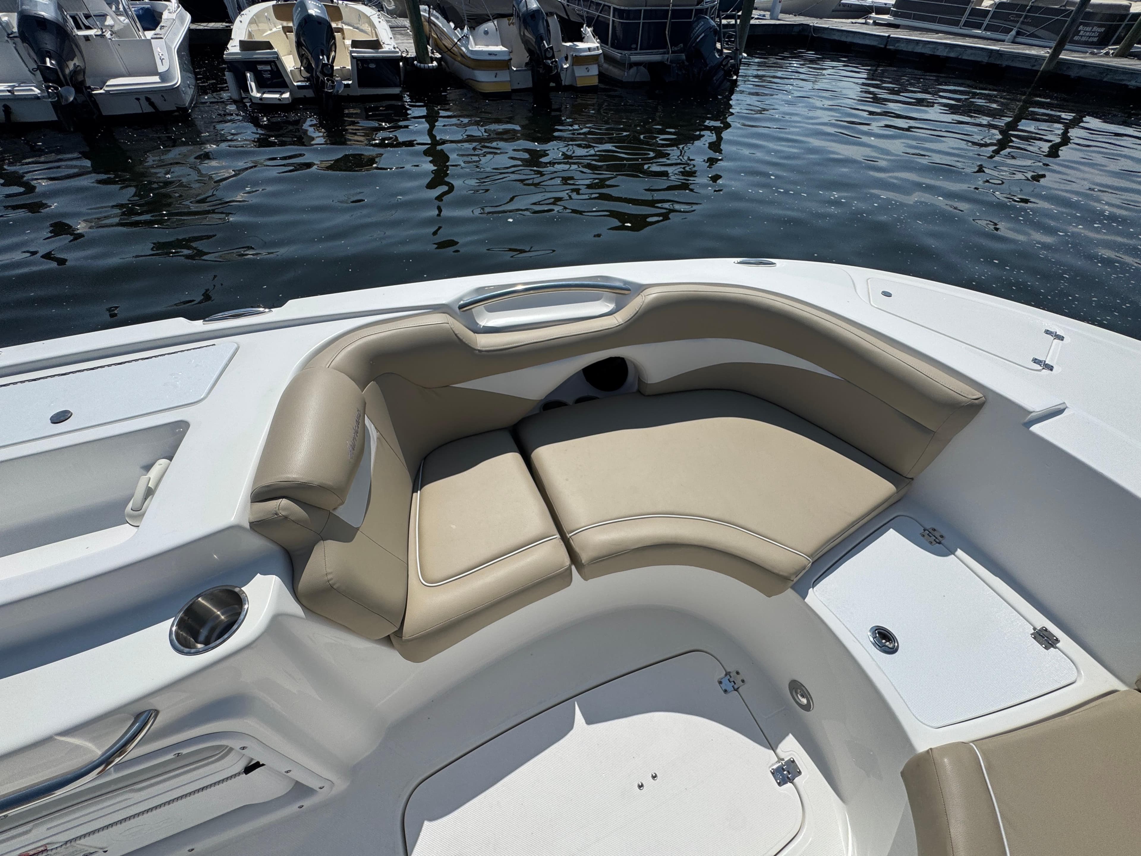 2017 Hurricane SunDeck Sport 203 OB boat interior with beige seating at a marina.