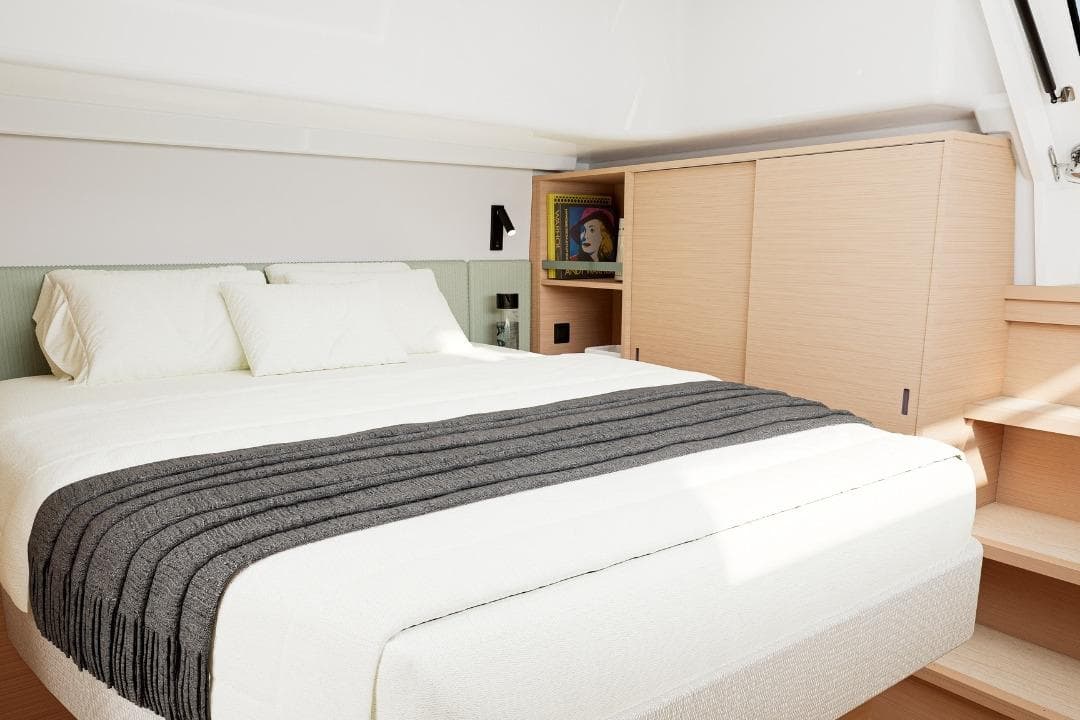 Luxurious bedroom interior of 2027 Lagoon 47 yacht with modern design and cozy bedding.