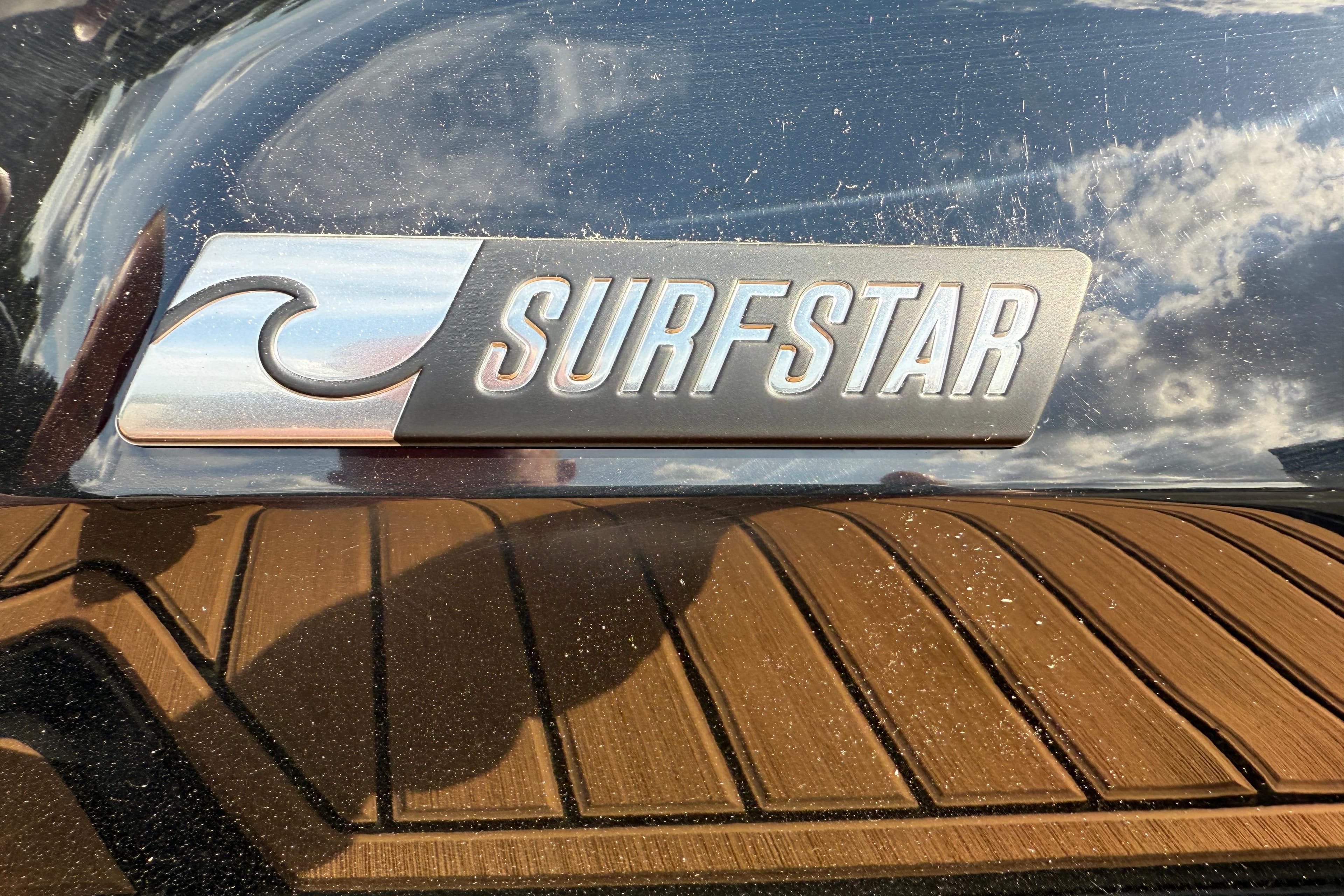 2025 MasterCraft X24 SurfStar logo on boat with wooden deck reflection.