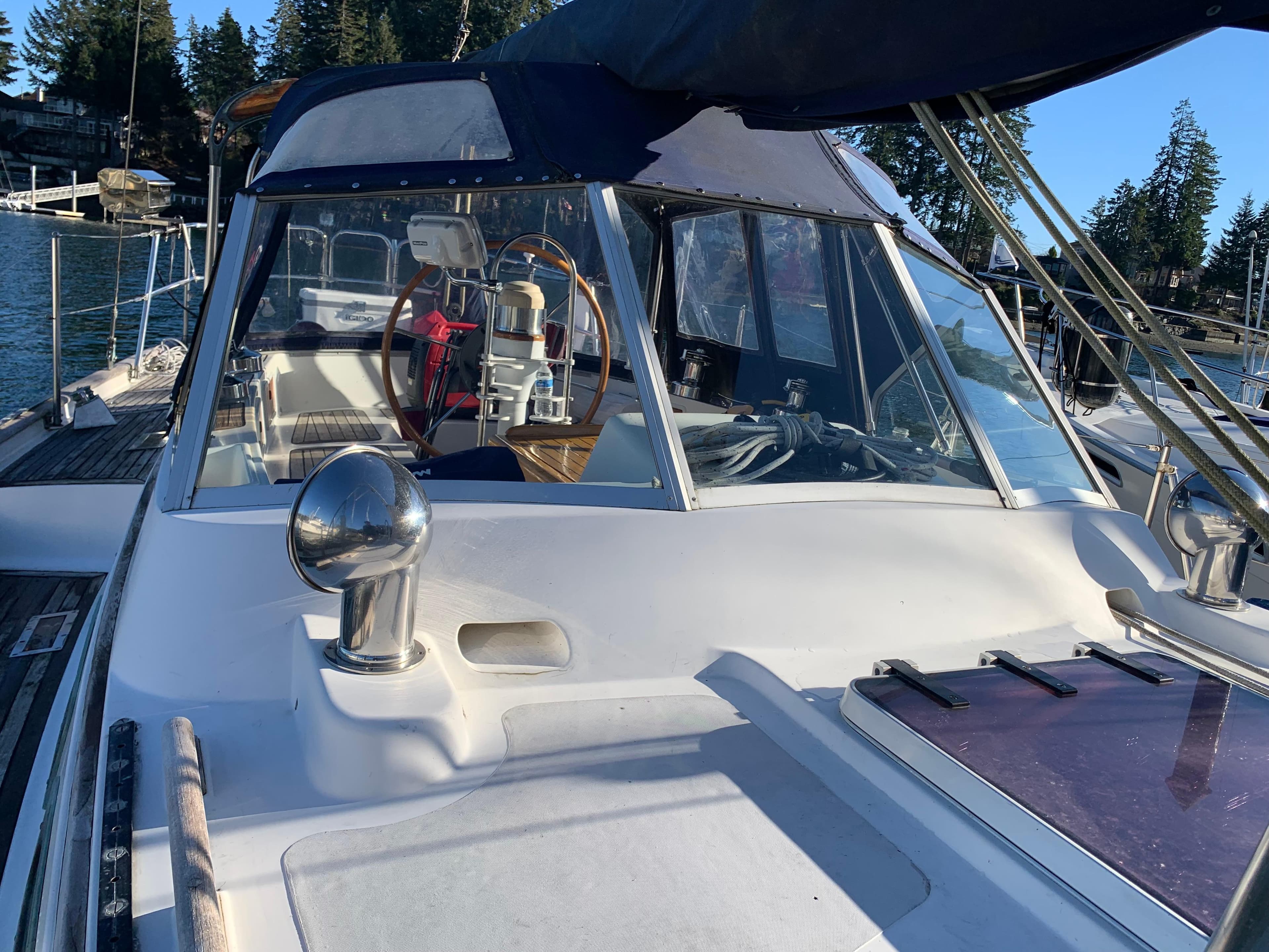1983 Liberty Center Cockpit sailboat with steering wheel, docked in a scenic marina.