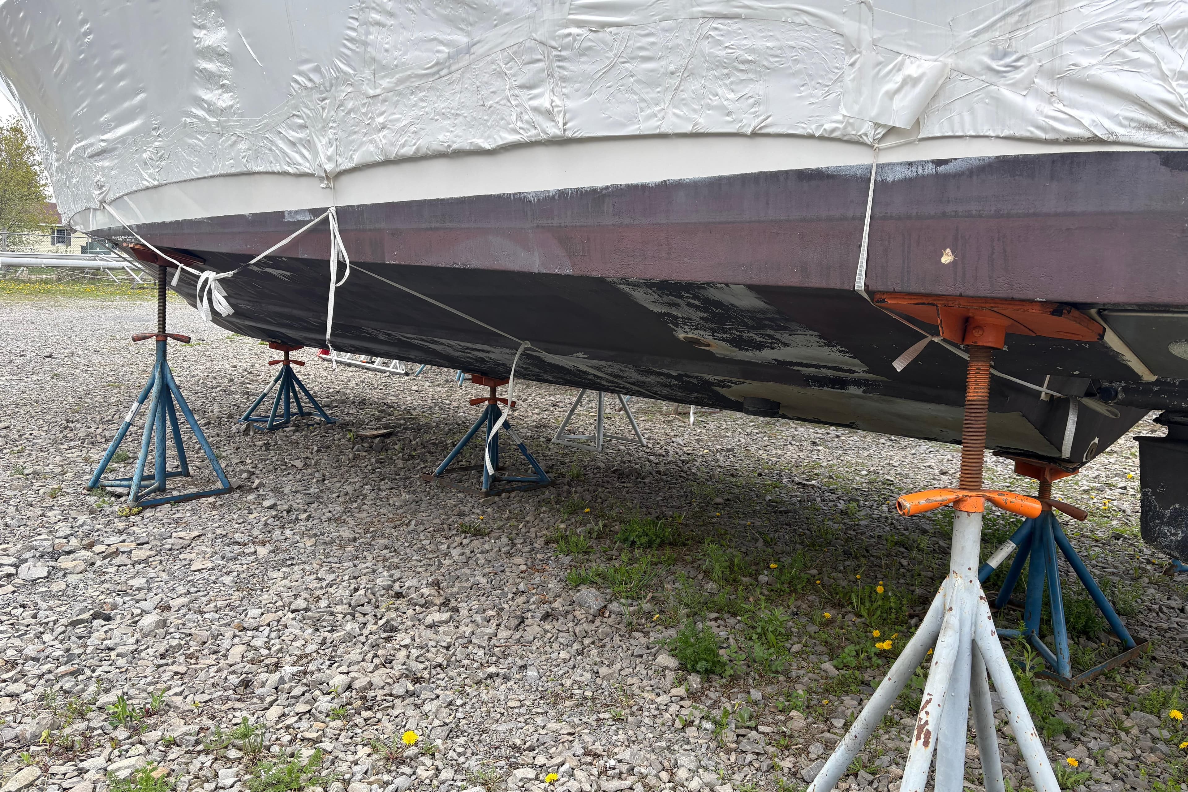 1999 Four Winns 328 Vista boat on stands, covered and stored on gravel.