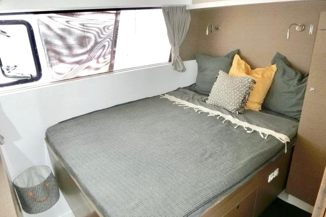 Cozy bedroom interior of 2020 NEEL 47 yacht with stylish bedding and window view.