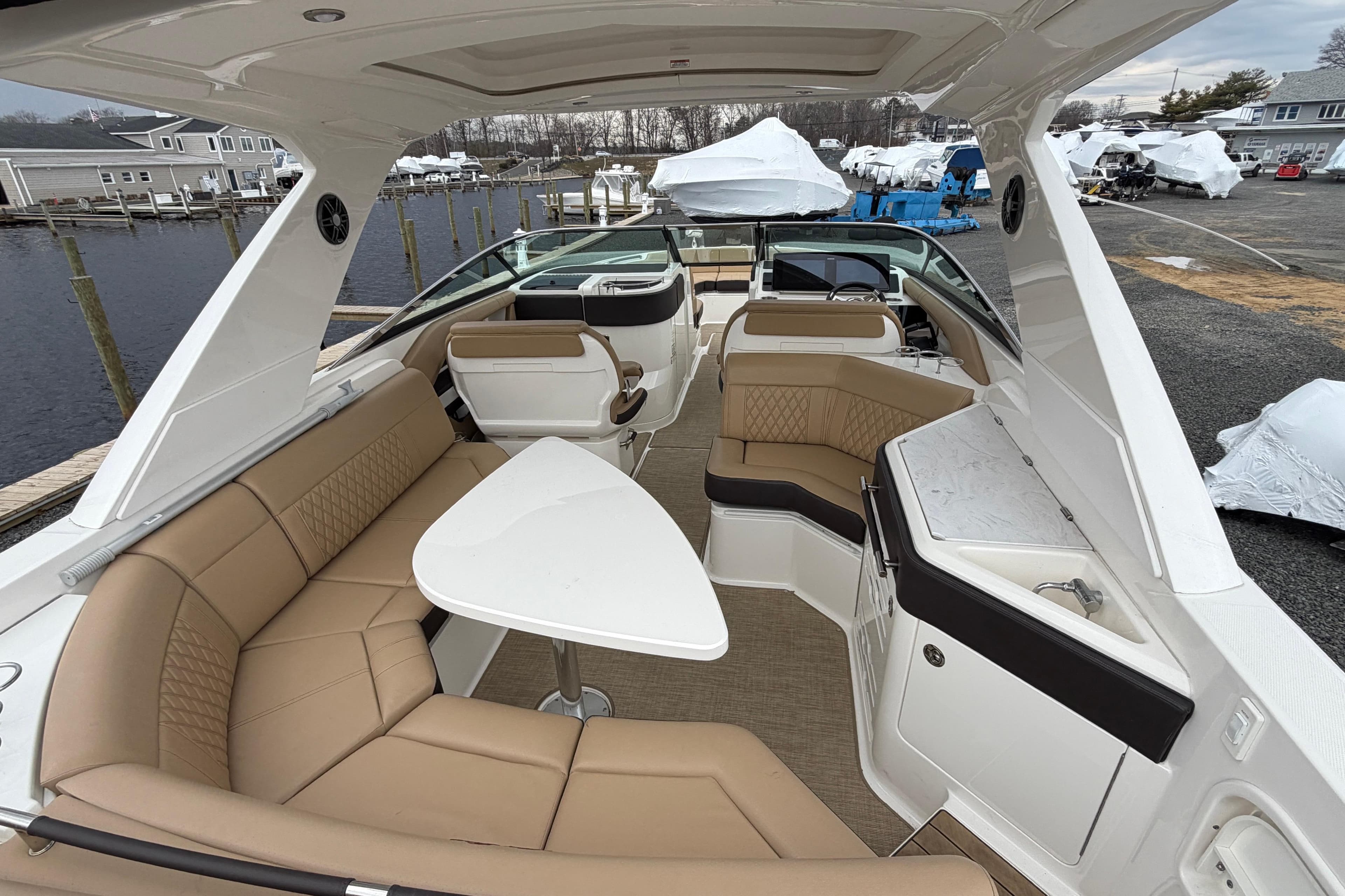 2023 Sea Ray SLX 310 Outboard interior with luxurious seating and table, docked at marina.
