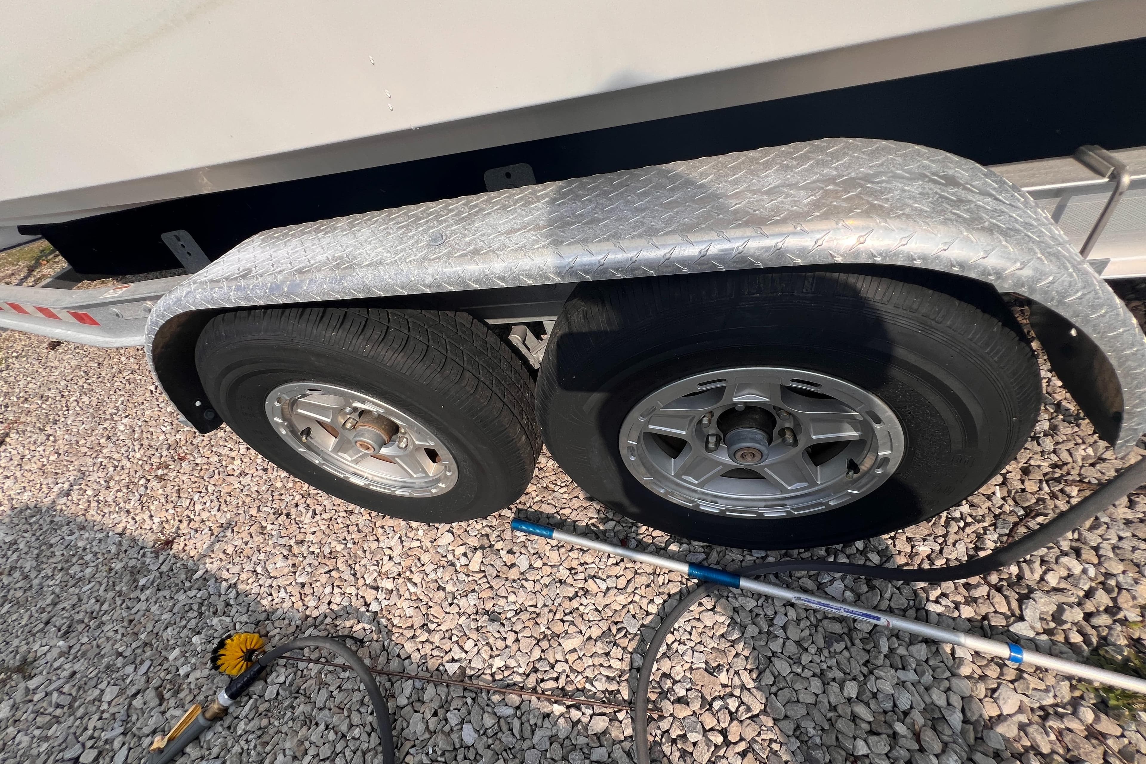 Trailer wheels of a 1995 Powerquest 290 Enticer FX on gravel.