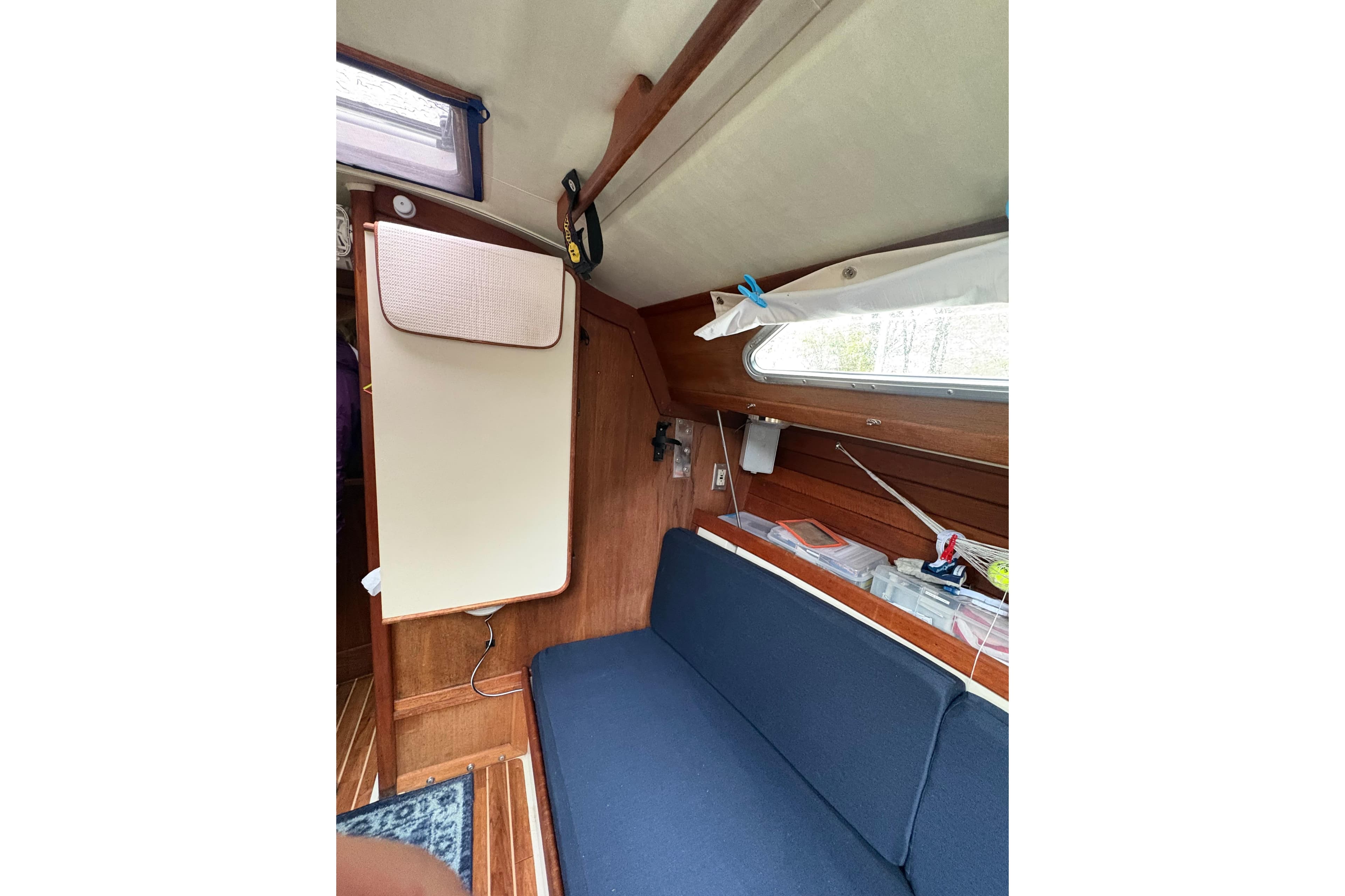 Interior of 1987 Ericson 28/2 sailboat with blue seating and wooden paneling.