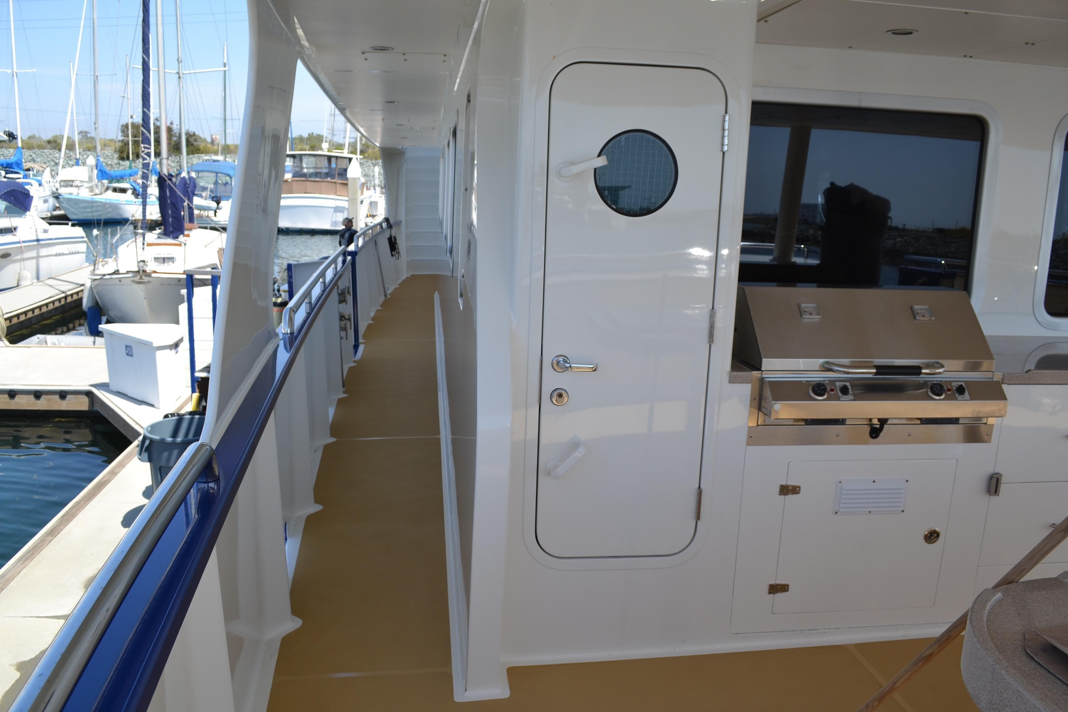 Side deck of 2018 Allseas Expedition yacht with outdoor grill and porthole door.