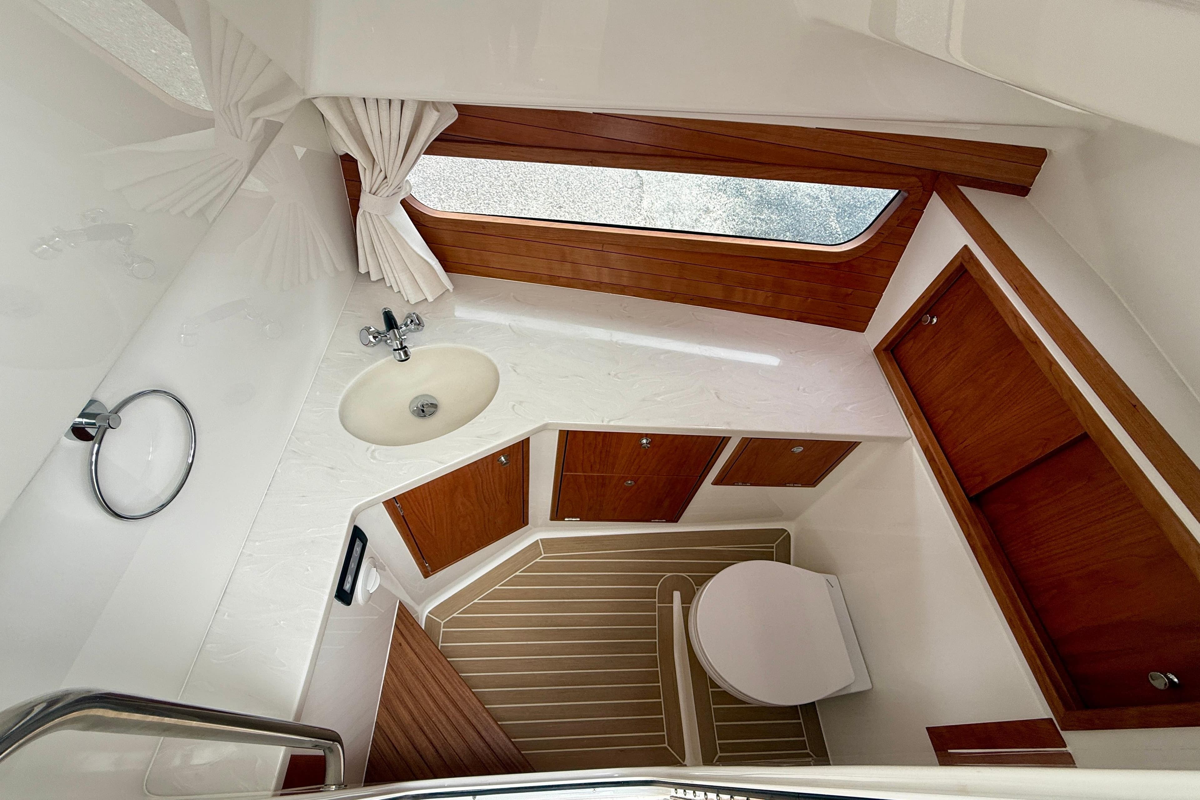 2026 MJM 38x yacht bathroom with wooden cabinets, sink, and toilet.