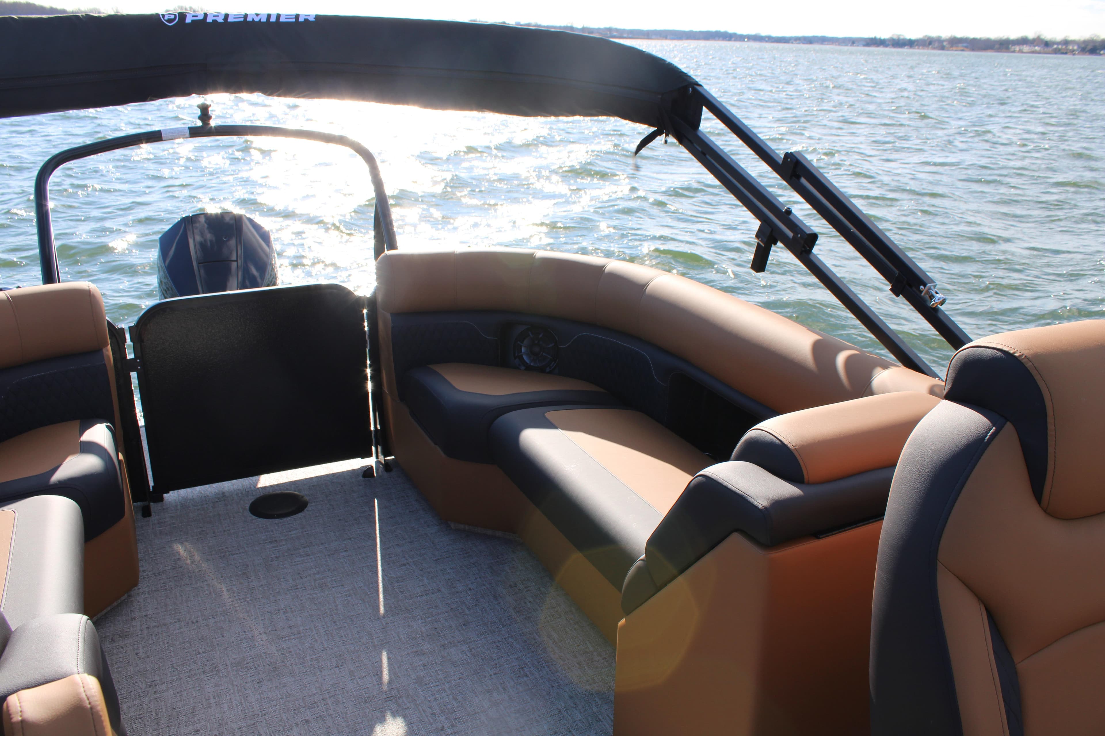 2026 Premier 230 SunSation RF pontoon boat interior with tan seating on a sunny day.