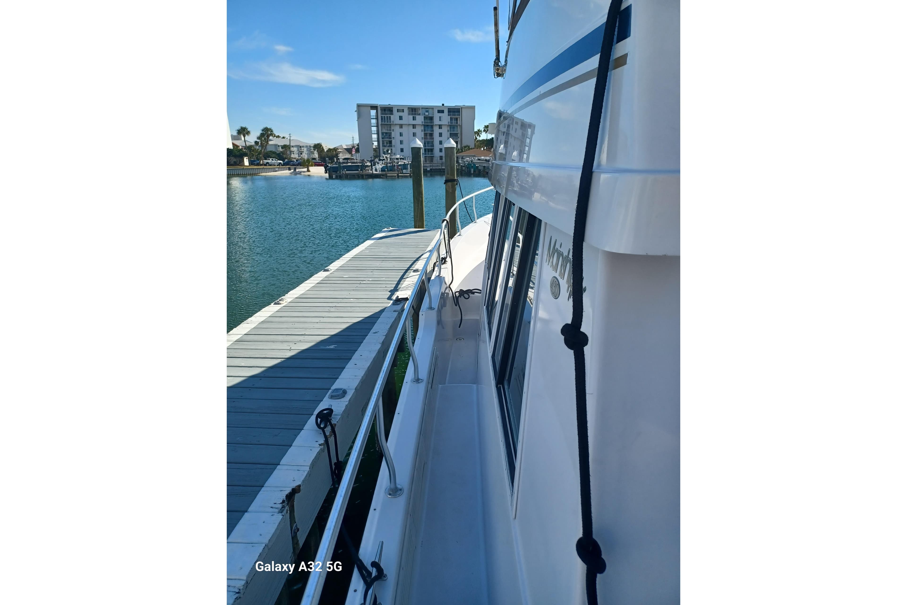 1999 Mainship 43 Trawler Aft Cabin docked at marina, sunny day, calm waters.