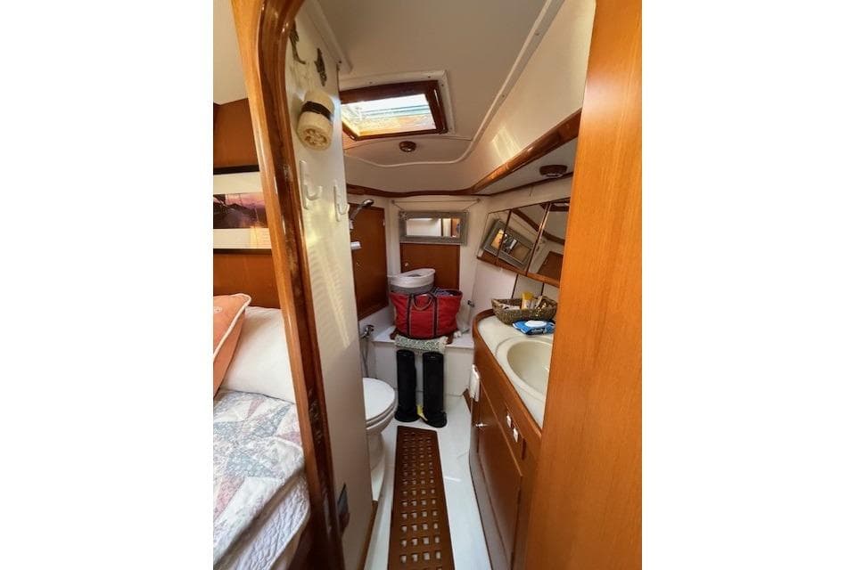 Interior of 2002 Hylas 46 yacht bathroom with wooden cabinetry and skylight.