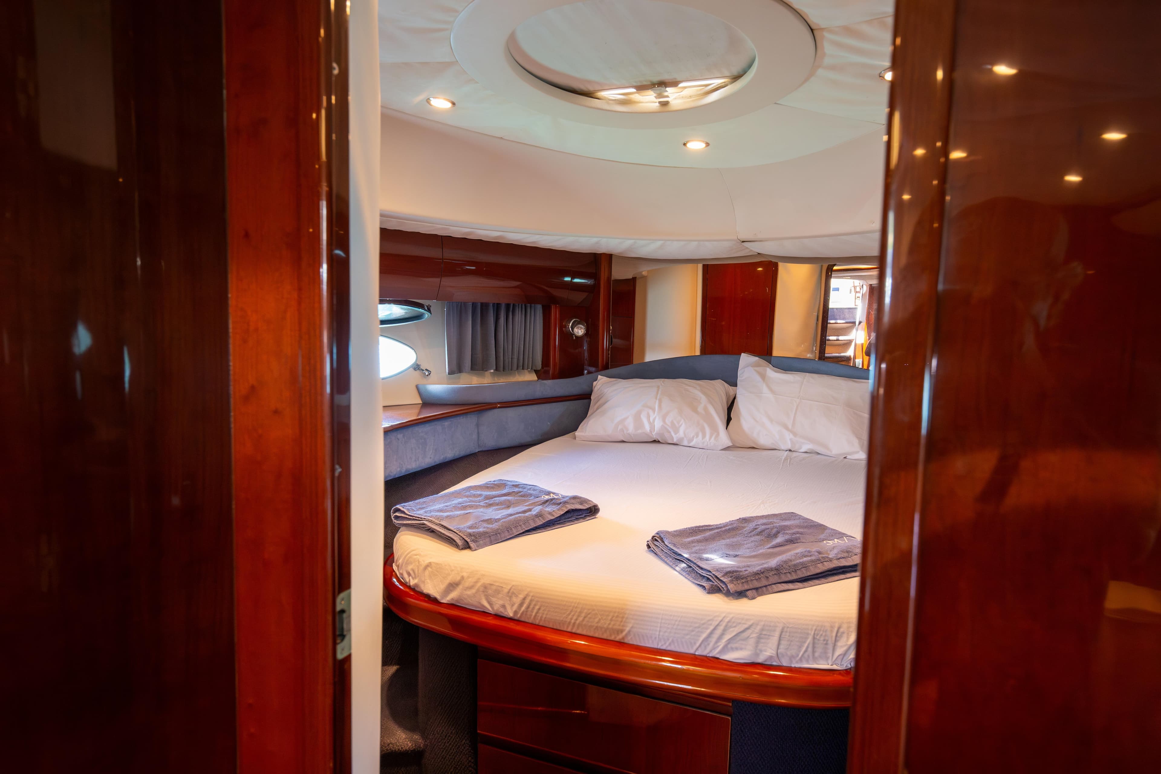 Luxurious cabin interior of 2004 Princess V65 yacht with cozy bed and elegant wood finish.