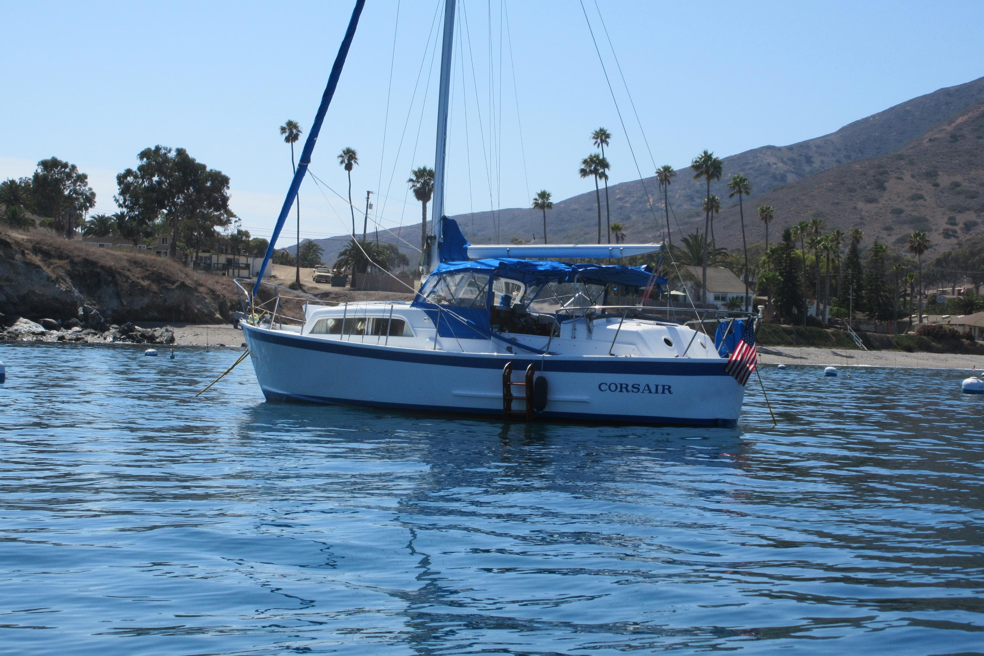 1963 Sumnercraft 31 Motor Sailer anchored near a scenic coastline with palm trees.
