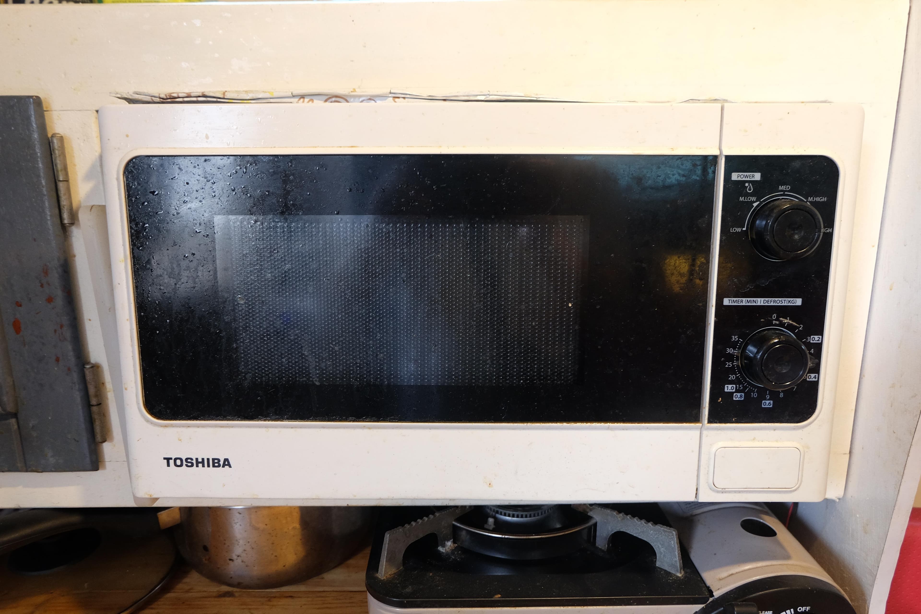 Vintage Toshiba microwave oven with dials, set in a kitchen environment.