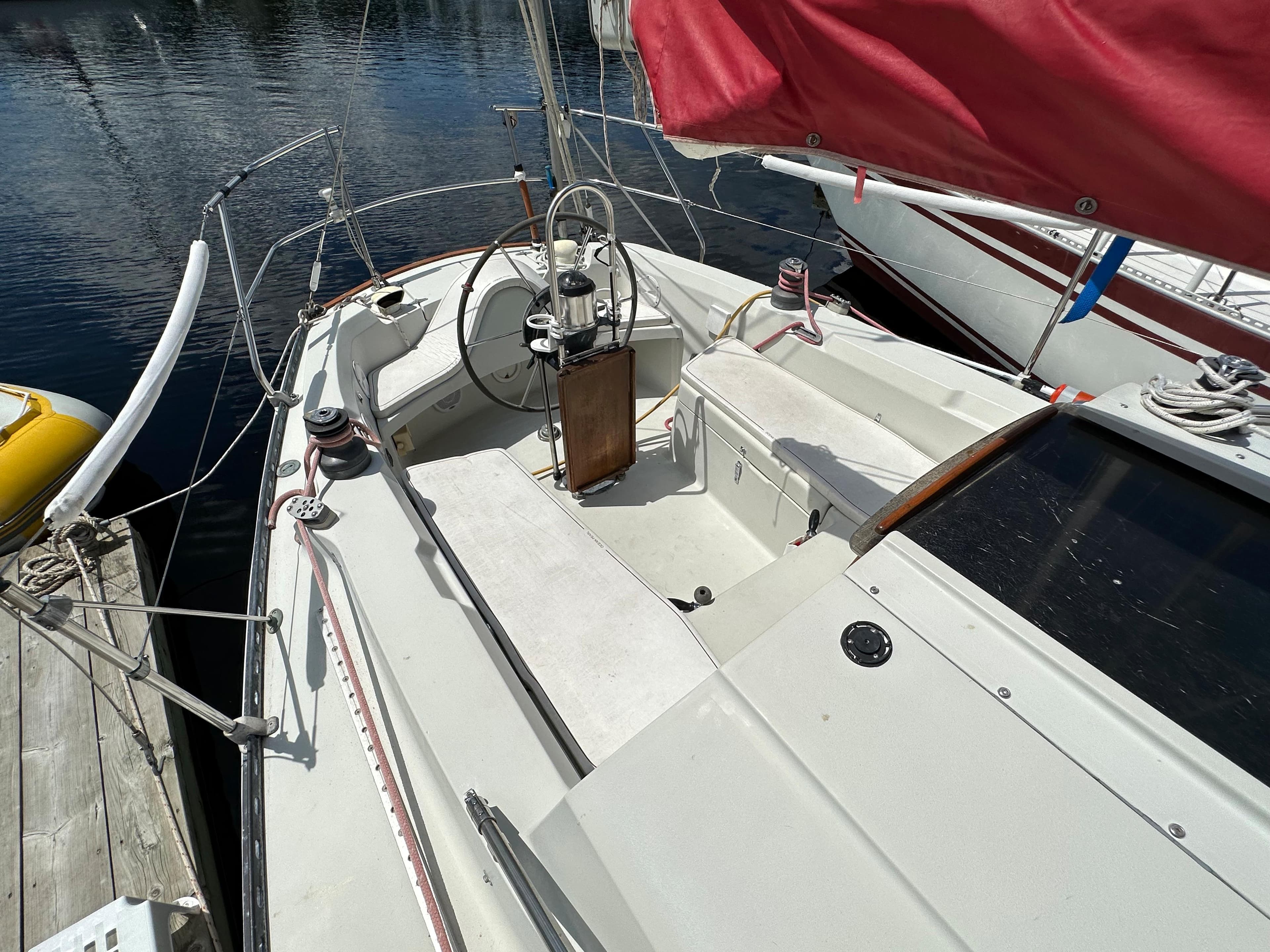 1982 C&C 32 sailboat cockpit with red sail, docked at marina.