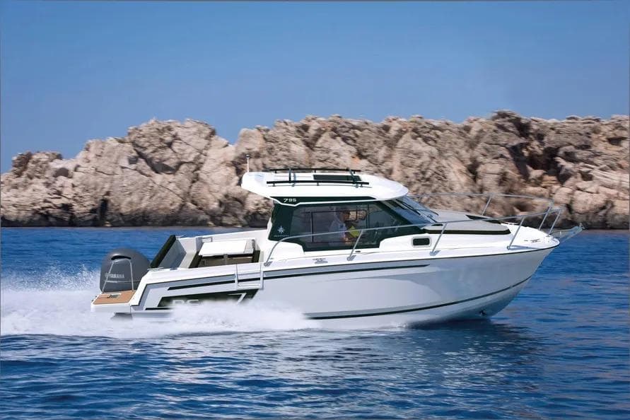 2026 Jeanneau NC 795 Series 2 boat cruising on blue water near rocky coastline.