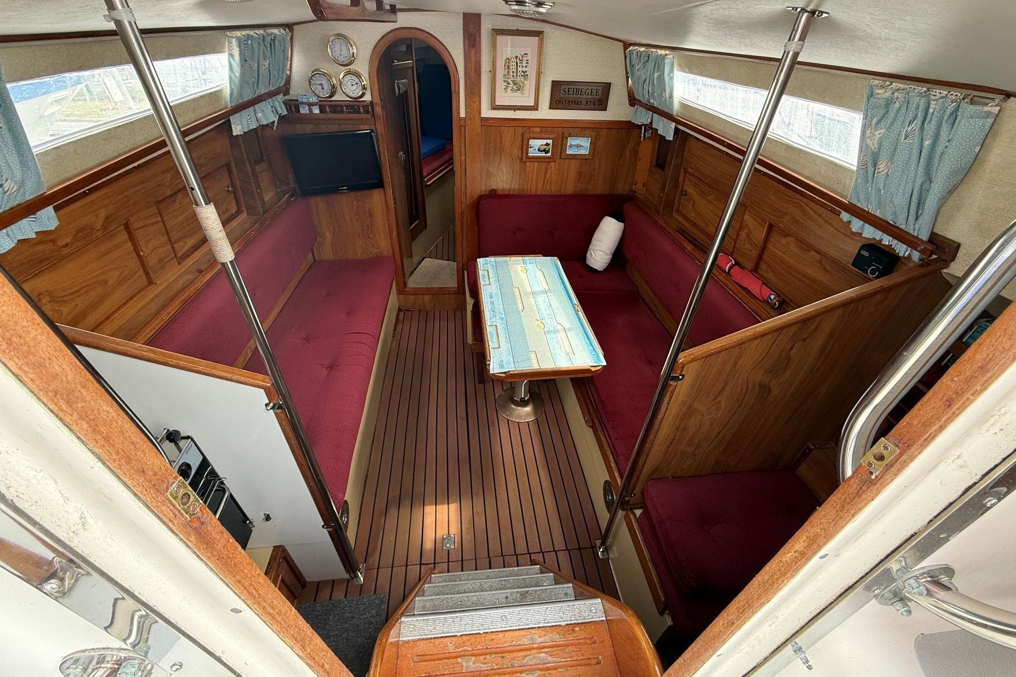 Interior of a 1978 Moody 30 sailboat with wood paneling and red seating.