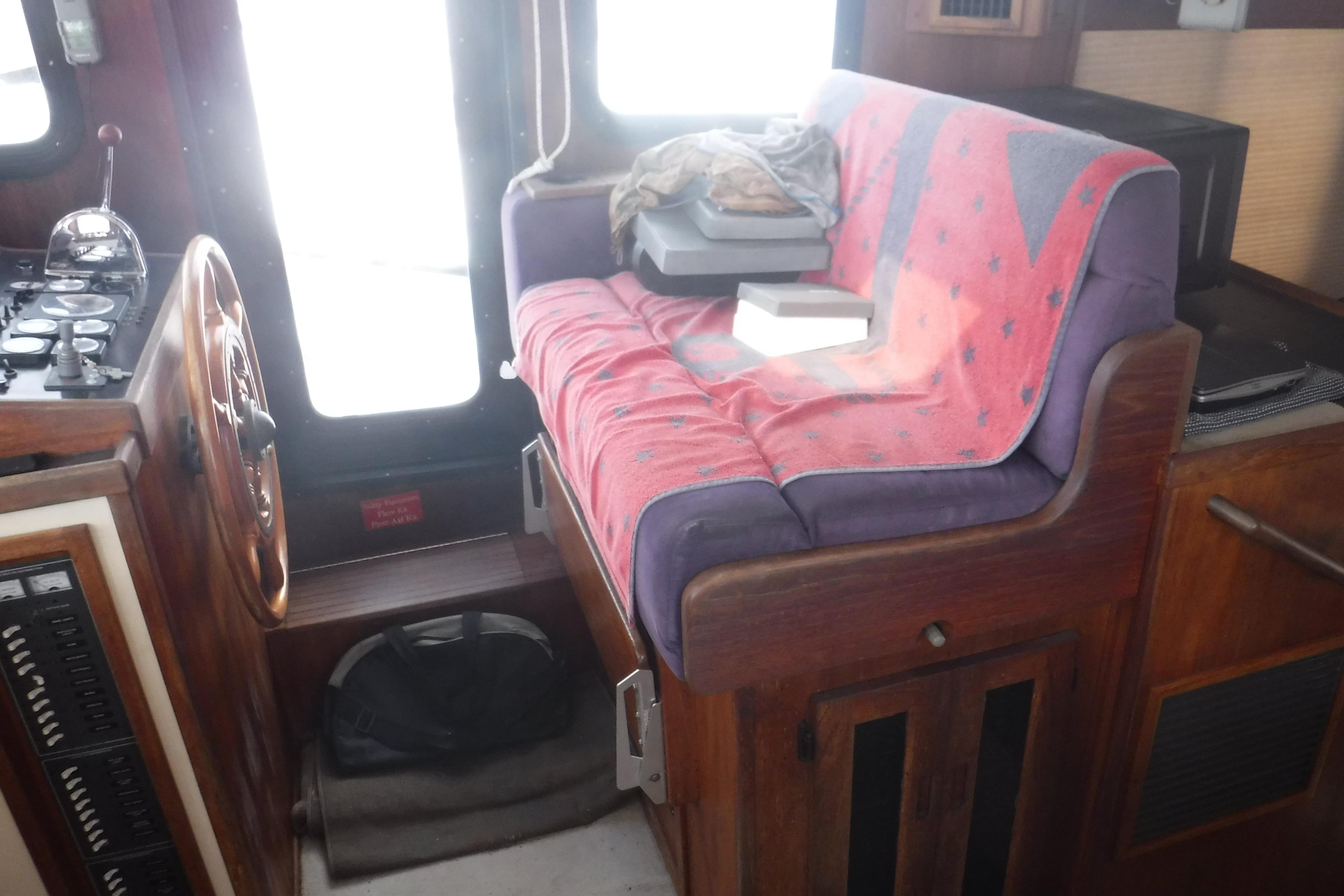 Cozy interior of a 2002 Nordic Tug 37 with a cushioned seat and nautical controls.