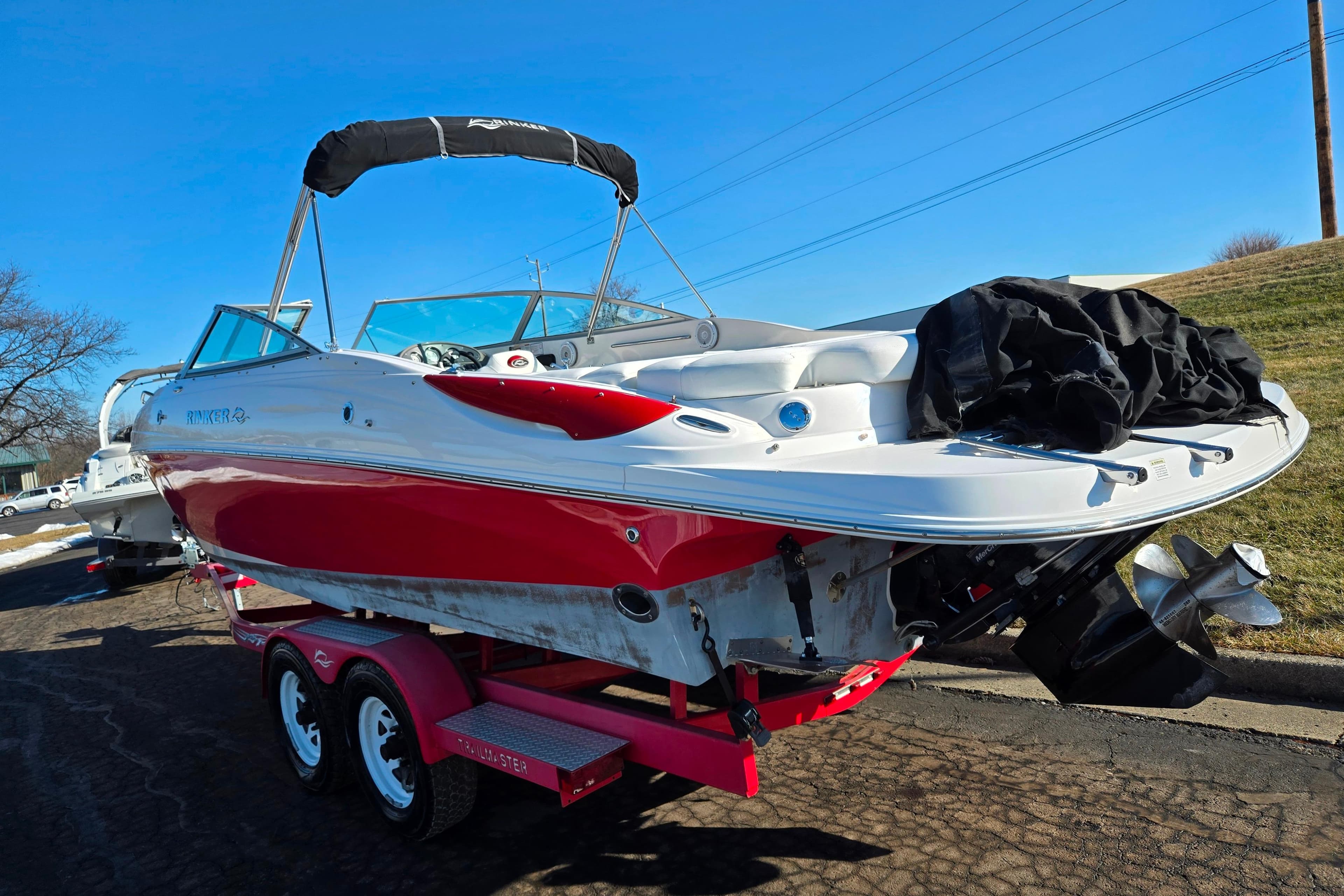 2007 Rinker 262 Captiva Cuddy boat on trailer, red and white design, sunny day.