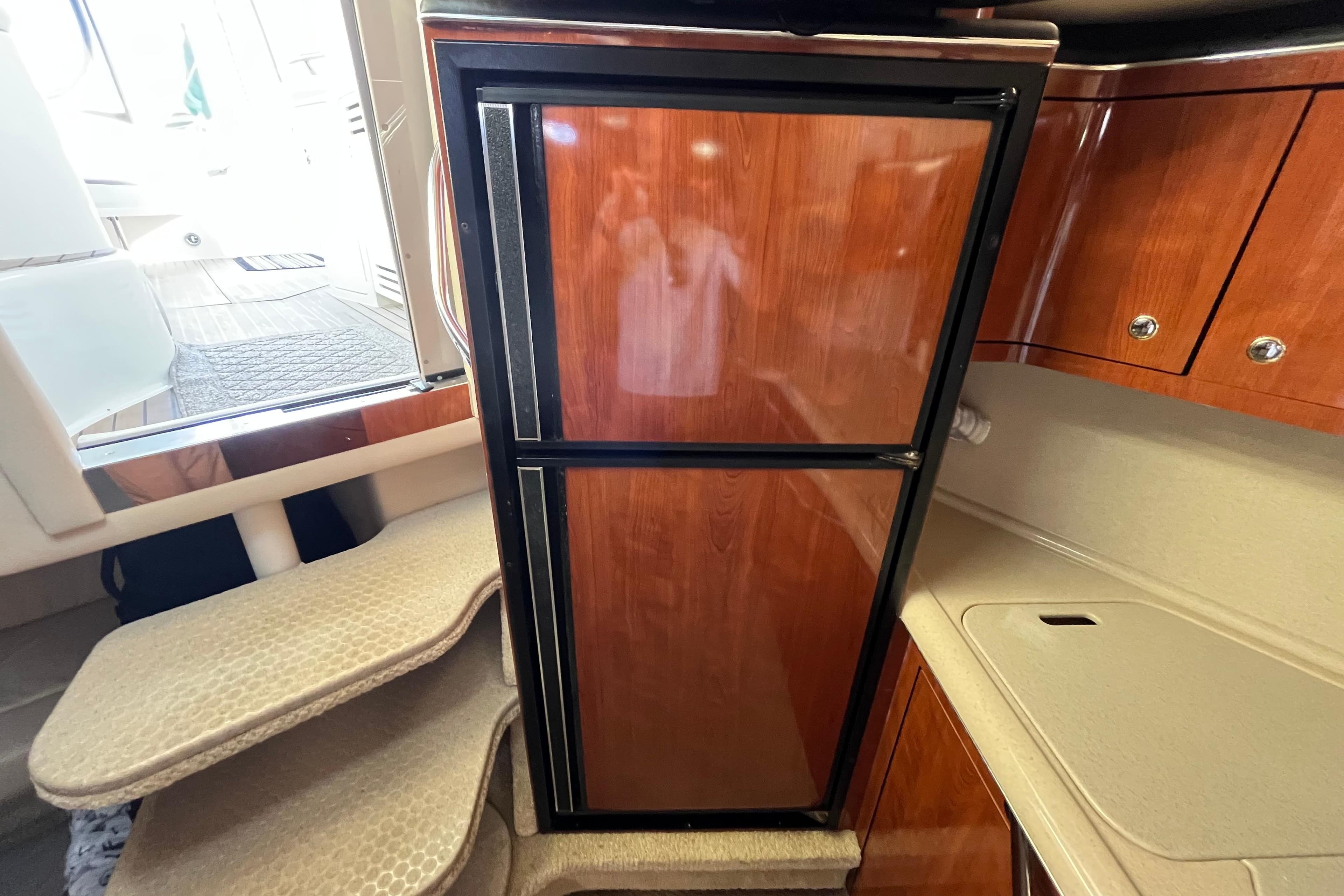 2003 Searay 380 yacht interior with wooden cabinetry and compact refrigerator.