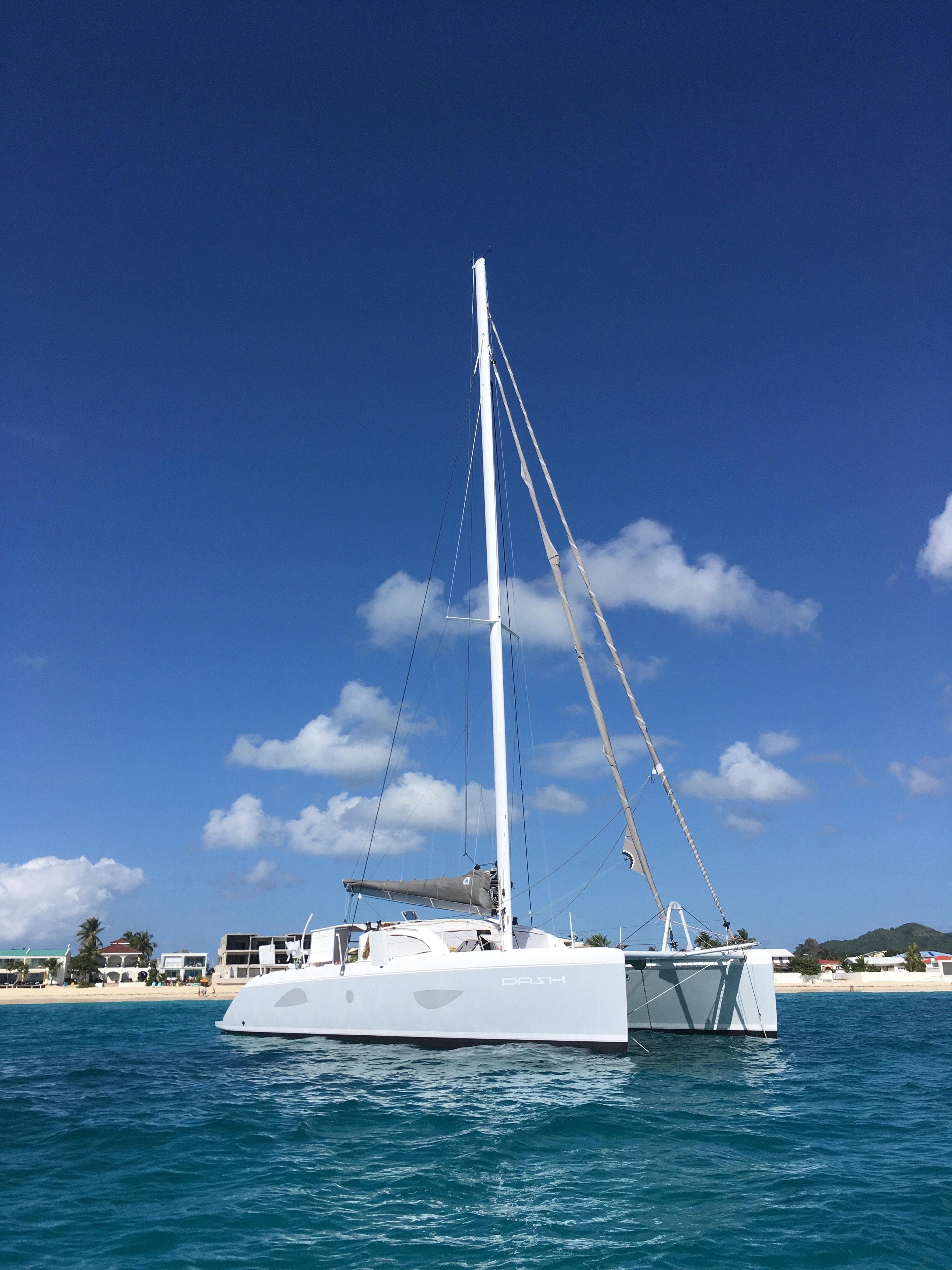 2010 Outremer 49 catamaran sailing on clear blue waters under a sunny sky.